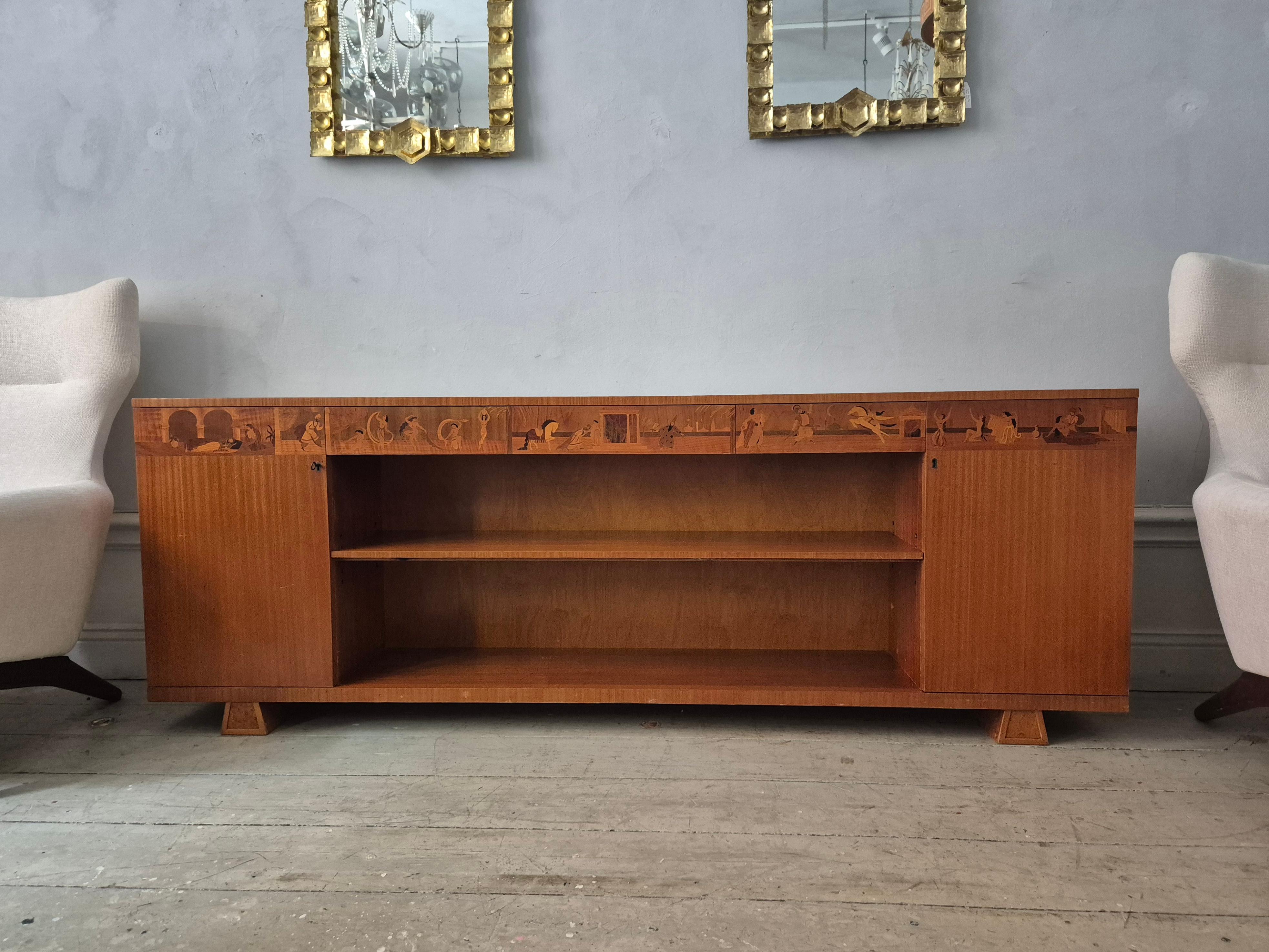 Low bookcase model Arabian Nights by Sven Ekholm and Erik Matsson for A/B Lamhults Stol- och snickerifabrik and Mjölby Intarsia. 

Made in Sweden 1930/40s. One cabinet with one shelf and one with two shelves. Three drawers with beautiful decor of