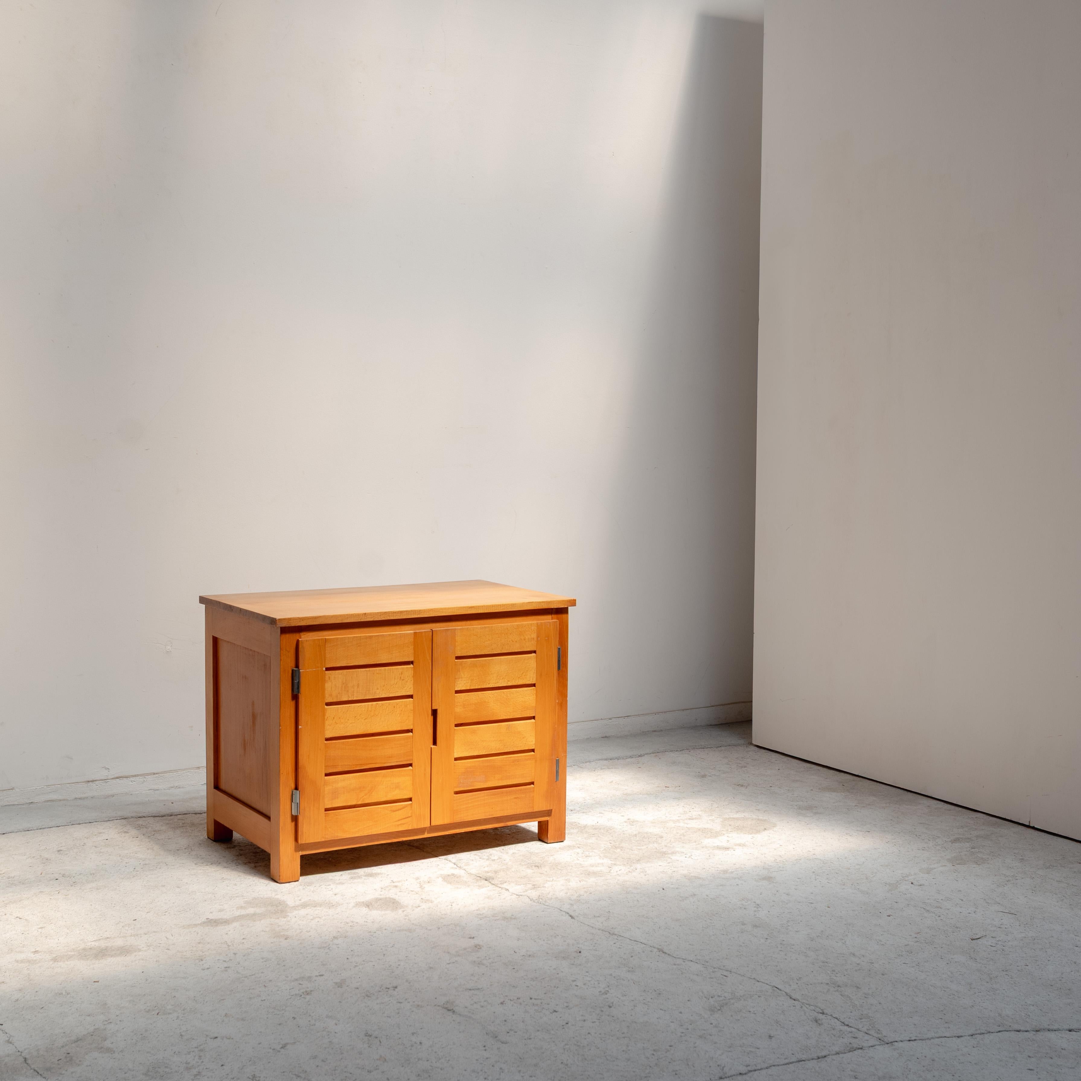 Ein kompakter Holzschrank, entworfen von Pierre Gautier-Delaye. Mit seiner warmen, natürlichen Maserung und den schlichten Lamellentüren spiegelt er die Fähigkeit des Designers wider, Klarheit und Harmonie in alltägliche Gegenstände zu