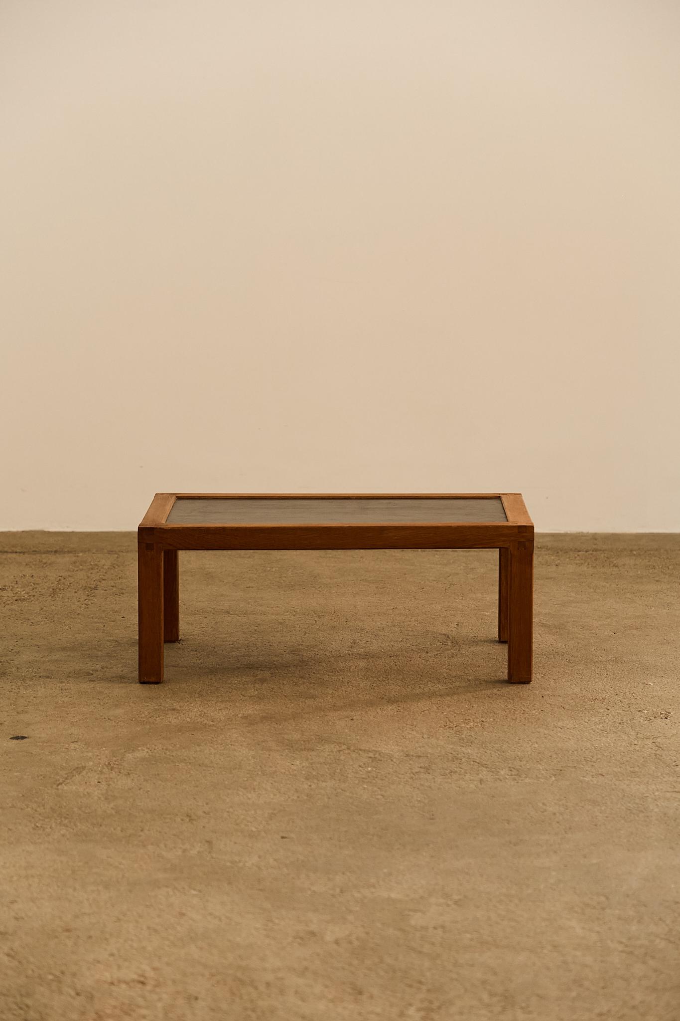 A low rectangular coffee table attributed to Pierre Chapo, crafted in solid oak with exposed mortise and tenon joints. The black leather inset top contrasts elegantly with the natural wood frame, highlighting Chapo’s architectural clarity and