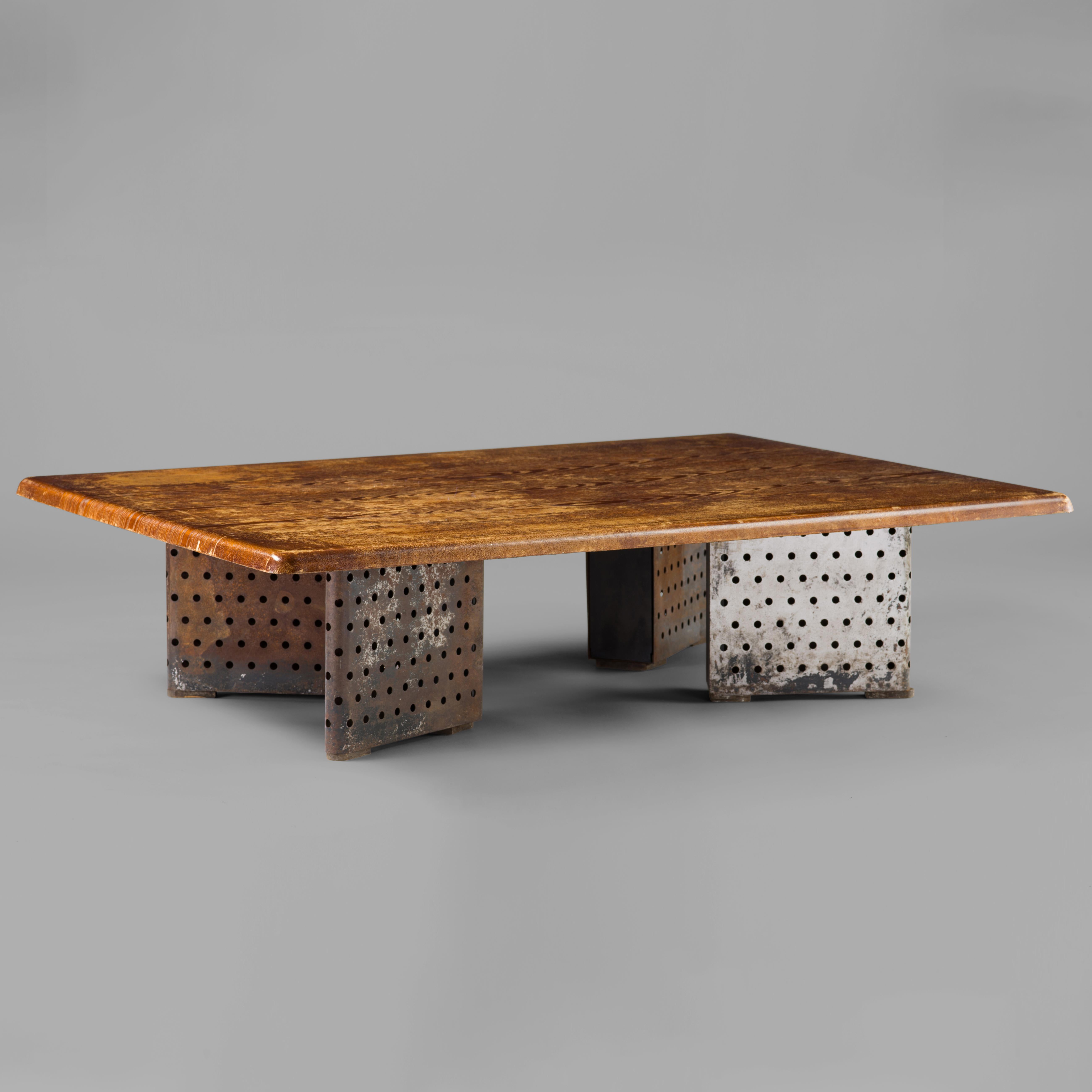 A low table comprising an oak-veneered wood top with bullnose edge supported by canted, wedge-shaped legs made from perforated steel sheet and stained wood, designed and manufactured by Marcel Yvroud for Cité Universitaire, Antony. There's scant