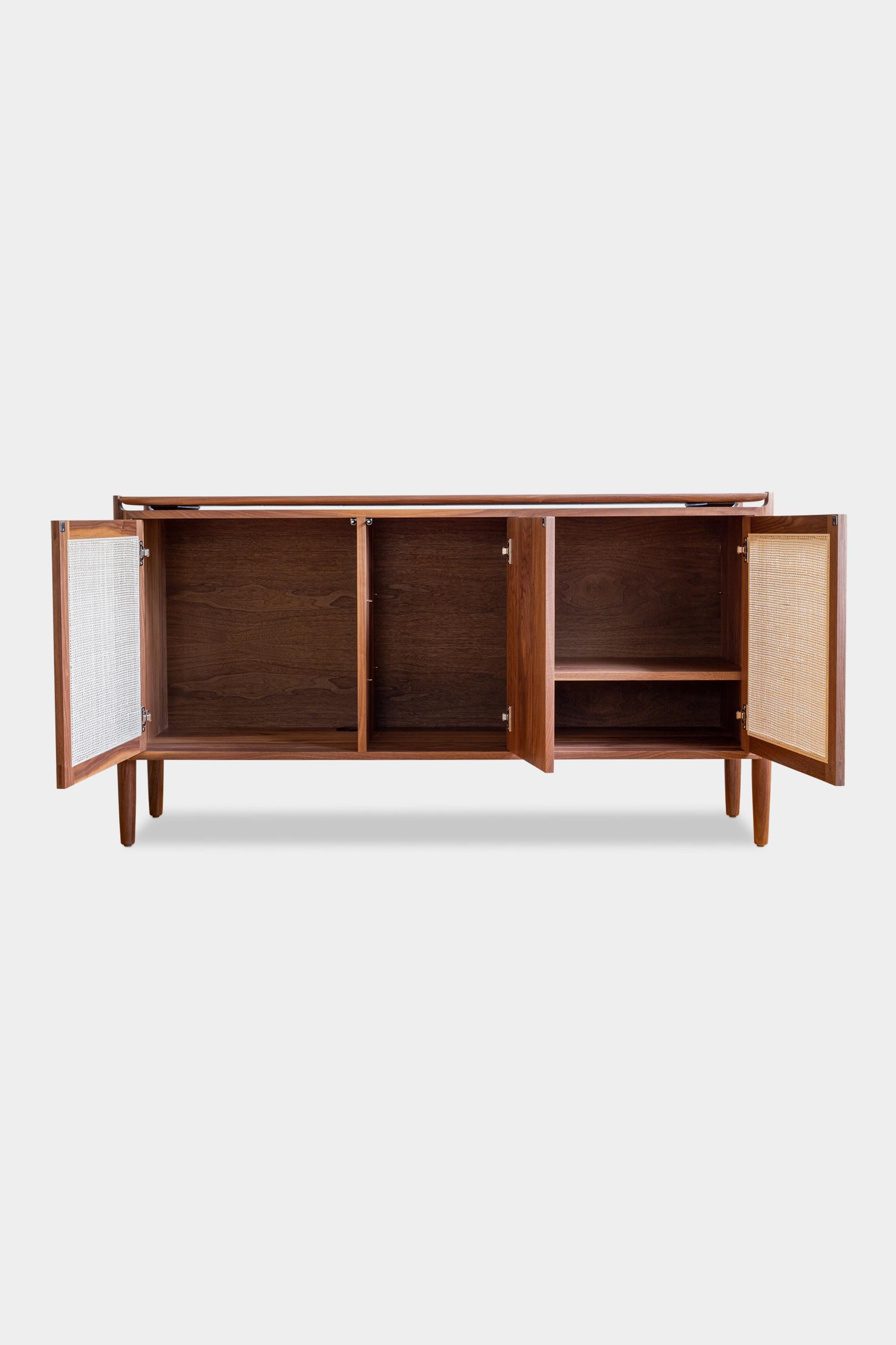 Solid wood constructed sideboard cabinet featuring hand-turned legs, hand-cut joinery and adjustable shelves. It details two push-to-open, cane detailed cabinet doors and one solid wood push-to-open cabinet door. There are custom configurations