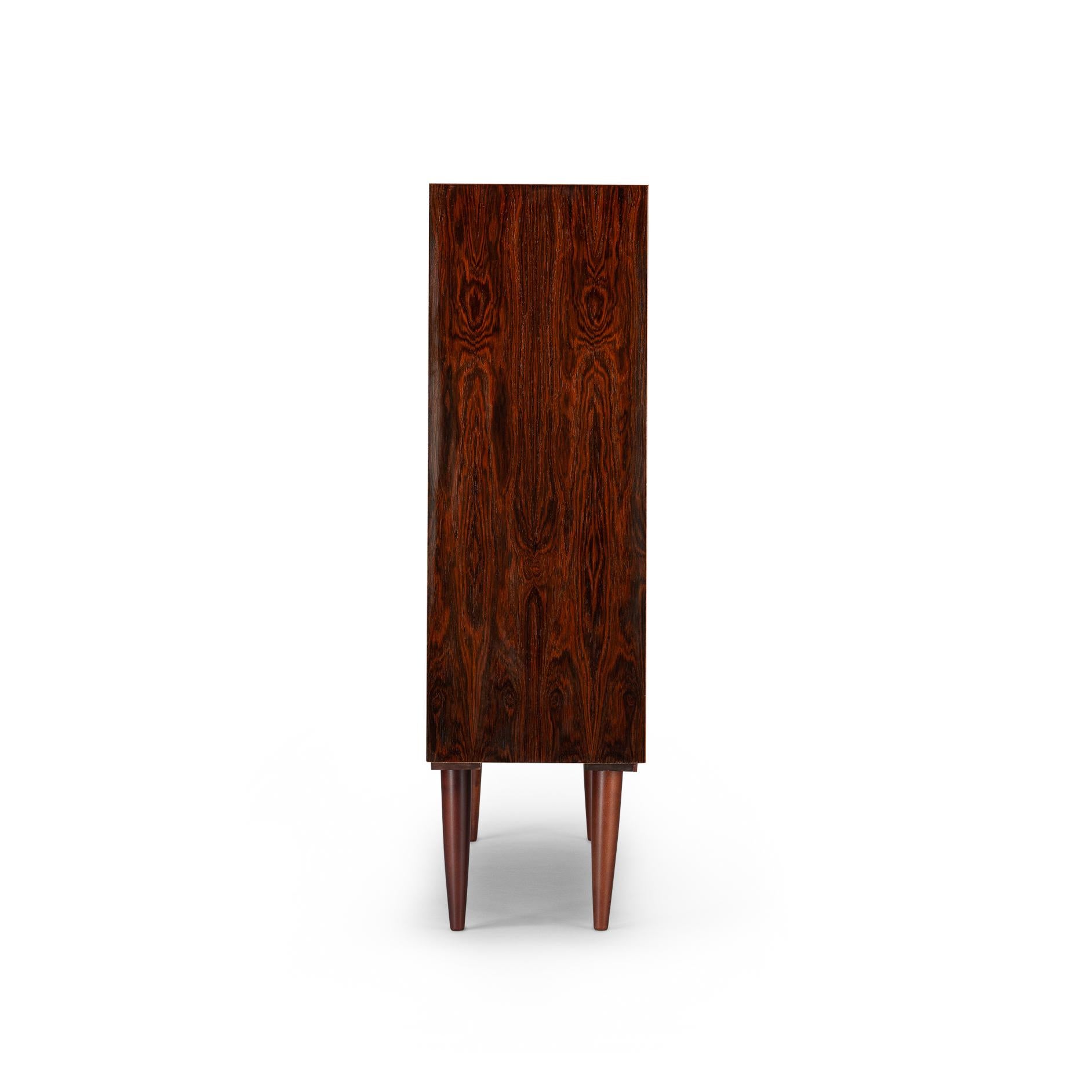 Danish low bookcase in beautiful expressive mahogany veneer. Designed by Carlo Jensen and made by Hundevad & Co. This bookcase is in very good vintage condition and has a total of 4 height-adjustable shelves.