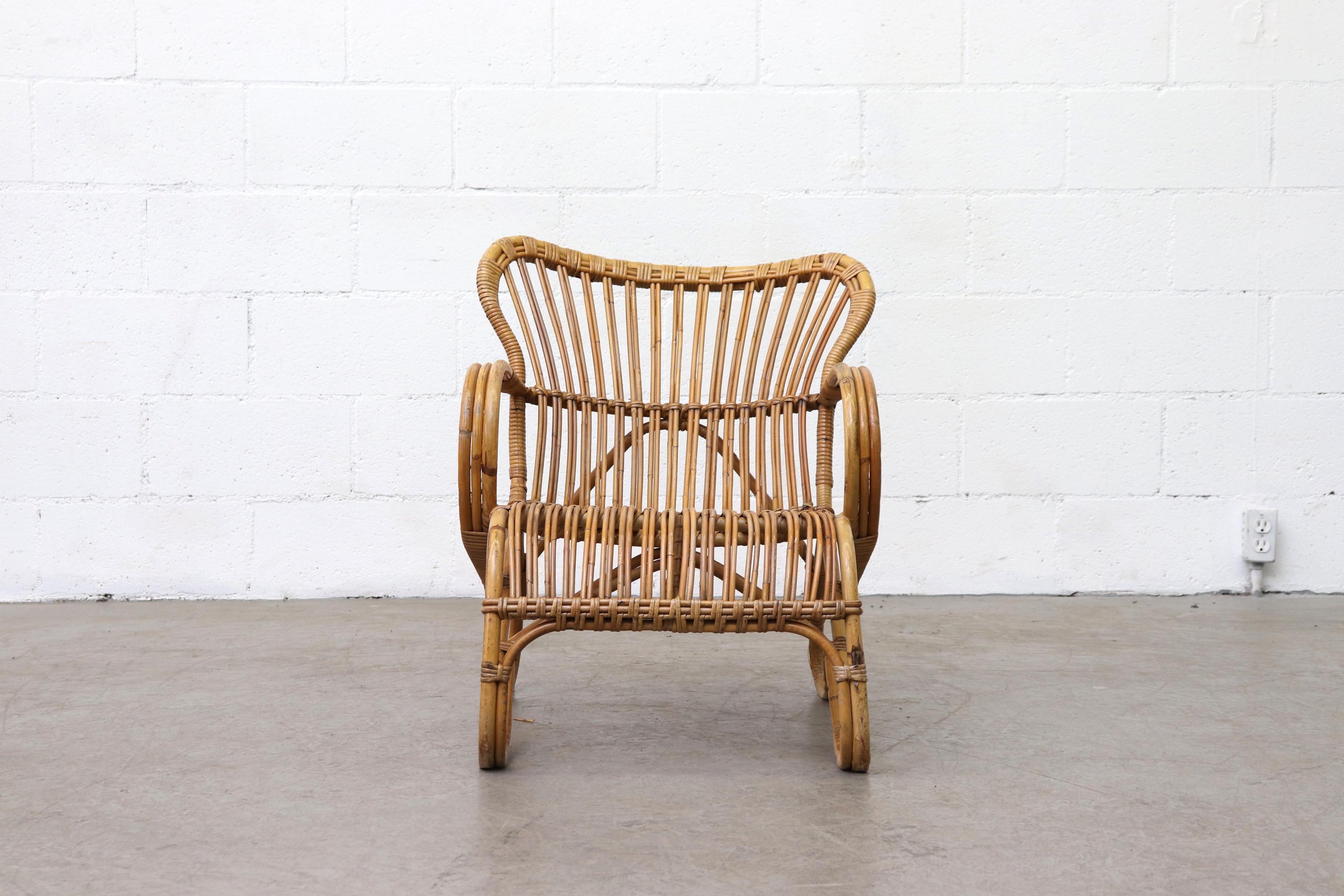 Low Midcentury bamboo rattan lounge chair. In original condition with visible signs of wear, including slight lean and shaved down feet. All wear is consistent with age and use. Other similar bamboo chairs available, listed separately.