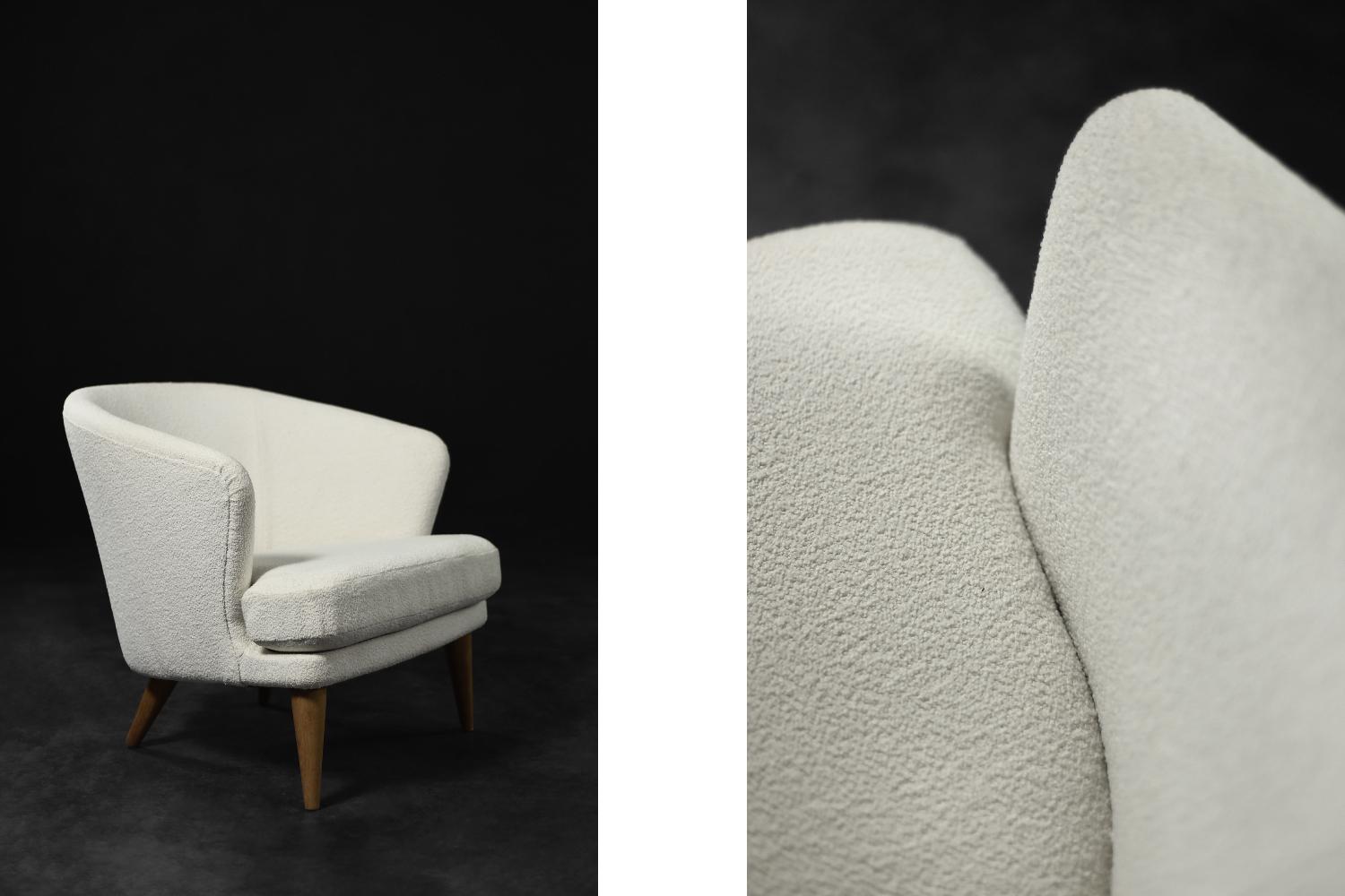 This low modernist armchair was produced in Scandinavia during the 1960s. It is characterized by a rounded backrest that flows smoothly into the armrests. The backrest and seat have been reupholstered with high-quality, thick, white fabric. The wide