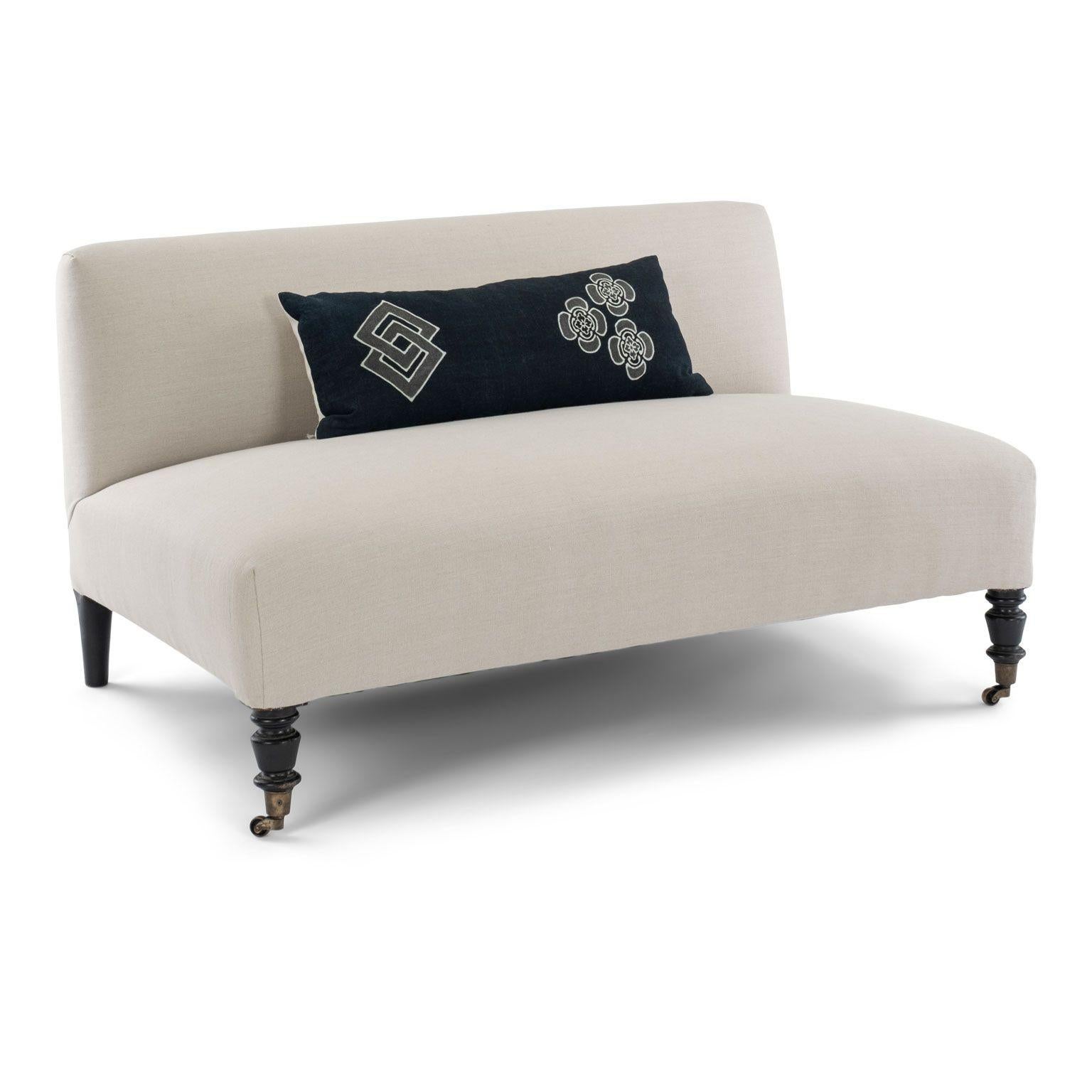 Low-profile Napoleon III French banquette, or settee, circa 1860-1879. Turned, ebonized legs front legs set into brass casters. Ebonized, hand-carved rear legs. Newly upholstered in neutral-color linen.