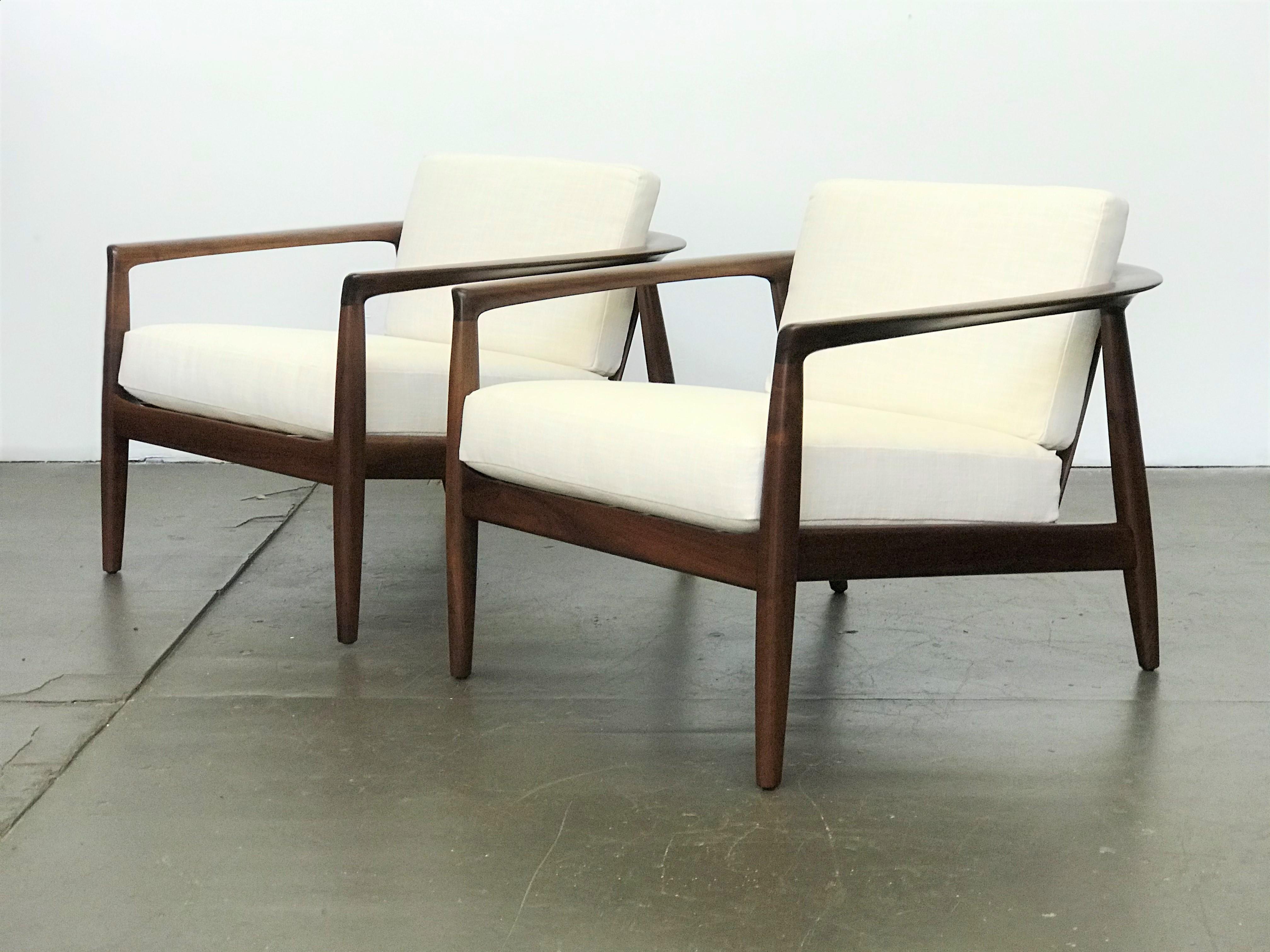 Excellent pair of walnut Swedish Modern low-profile slat back lounge chairs by Folke Ohlsson for Dux - 1950's. Model 72-C. Refinished walnut frames. New straps and cushions with off-white linen upholstery. These striking chairs have wonderful lines