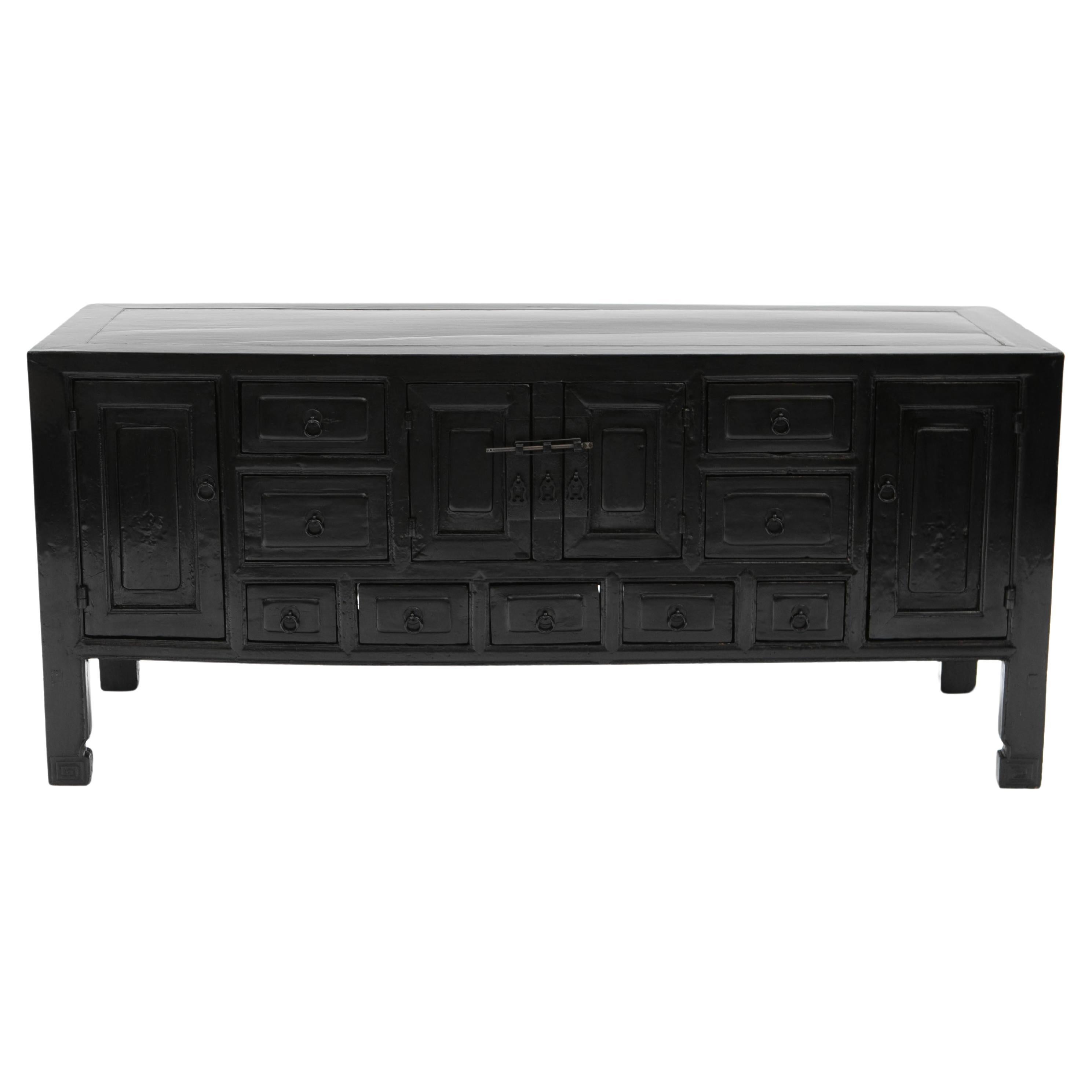 A Chinese art deco kang (low) cabinet or sideboard from the Hebei Province 1910-1920.

Chinese Qing dynasty low sideboard, also known as a kang (low) cabinet, with black lacquer.
Front with 9 drawers, a door on each side, and a pair of doors in the