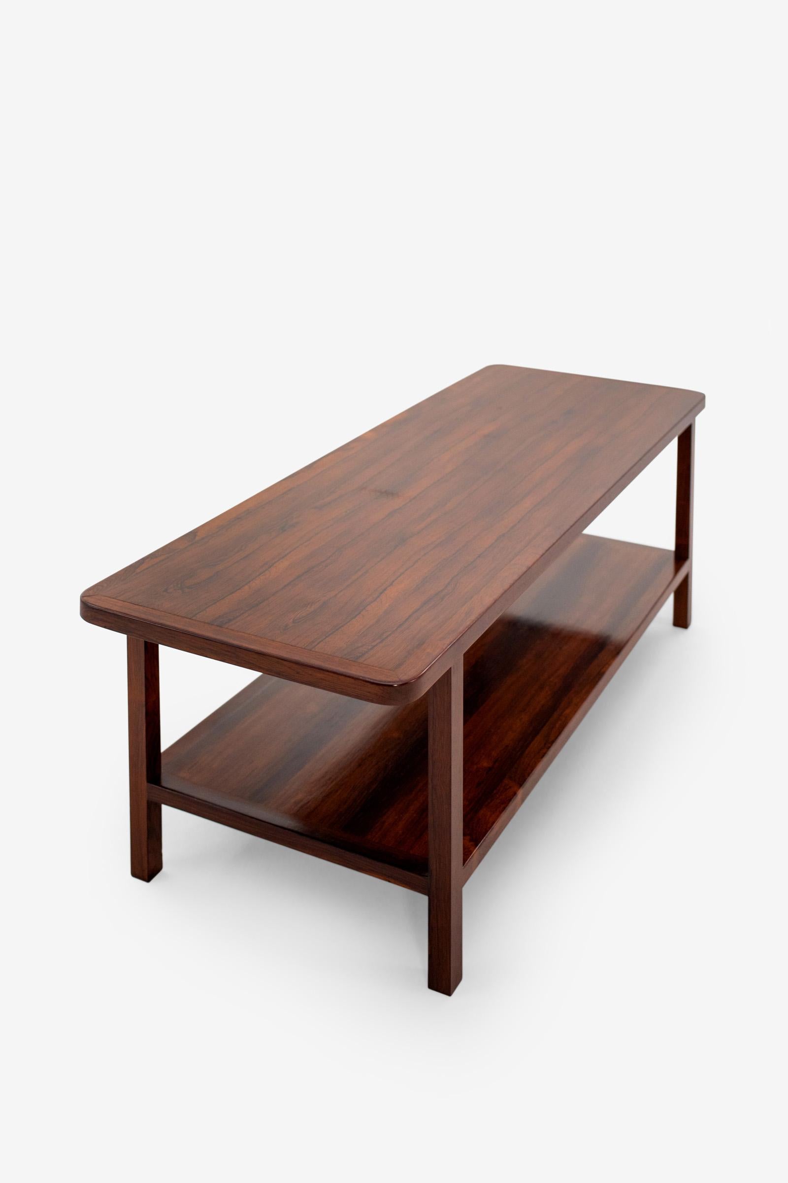 Una pieza minimalista de palisandro con bordes suavizados y un estante abierto. Sobrio y finamente proporcionado, es
refleja la creencia de Tenreiro en la belleza a través de la sencillez y la artesanía.