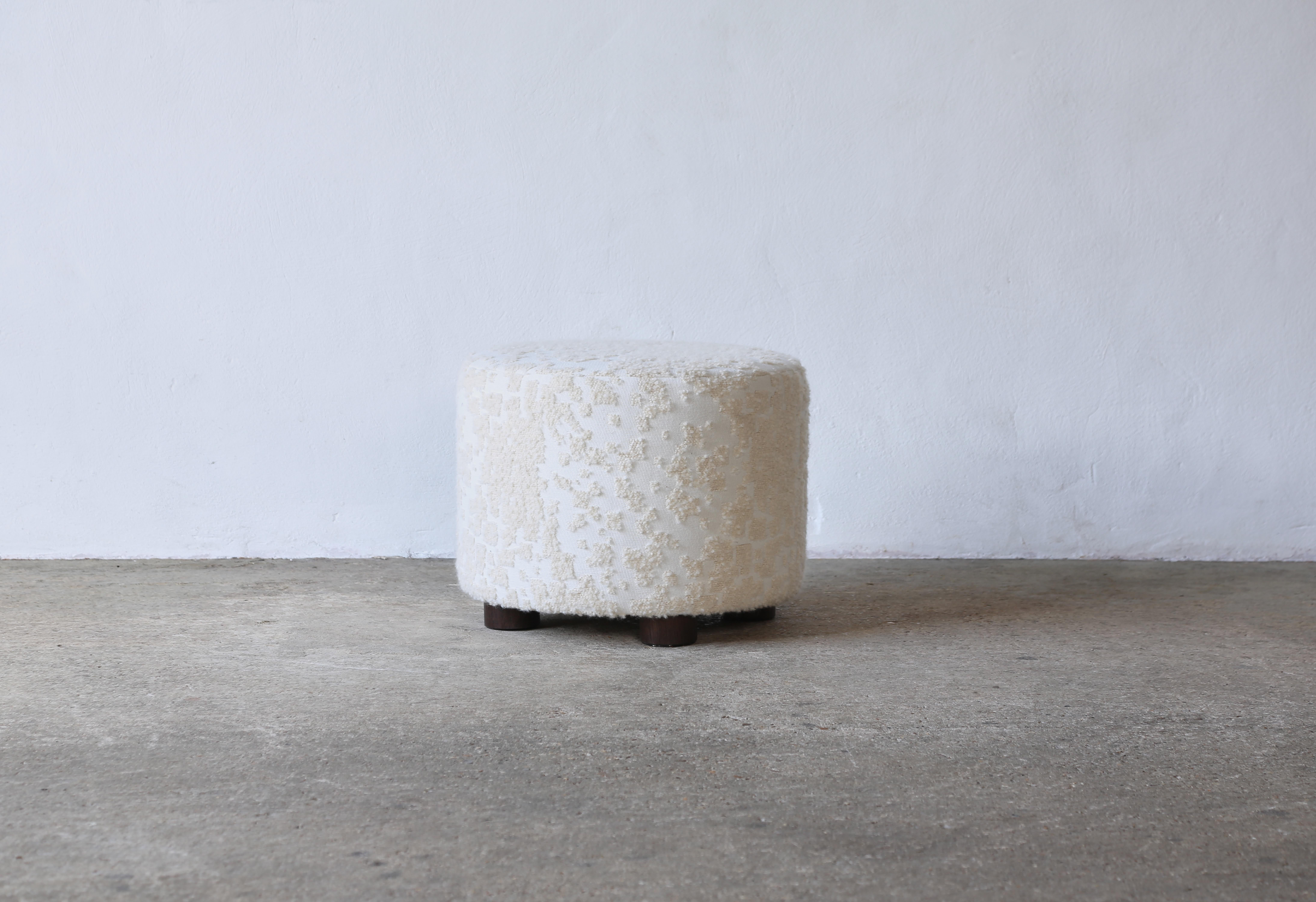 Un ottoman élégant, moderne, bas et rond.  Fabriqué à la main en Angleterre.  Nouvellement tapissé en tissu Holly Hunt Donatella Winter White, avec des pieds en chêne massif.   Le tissu est tissé dans l'une des meilleures usines de mode d'Italie. Il