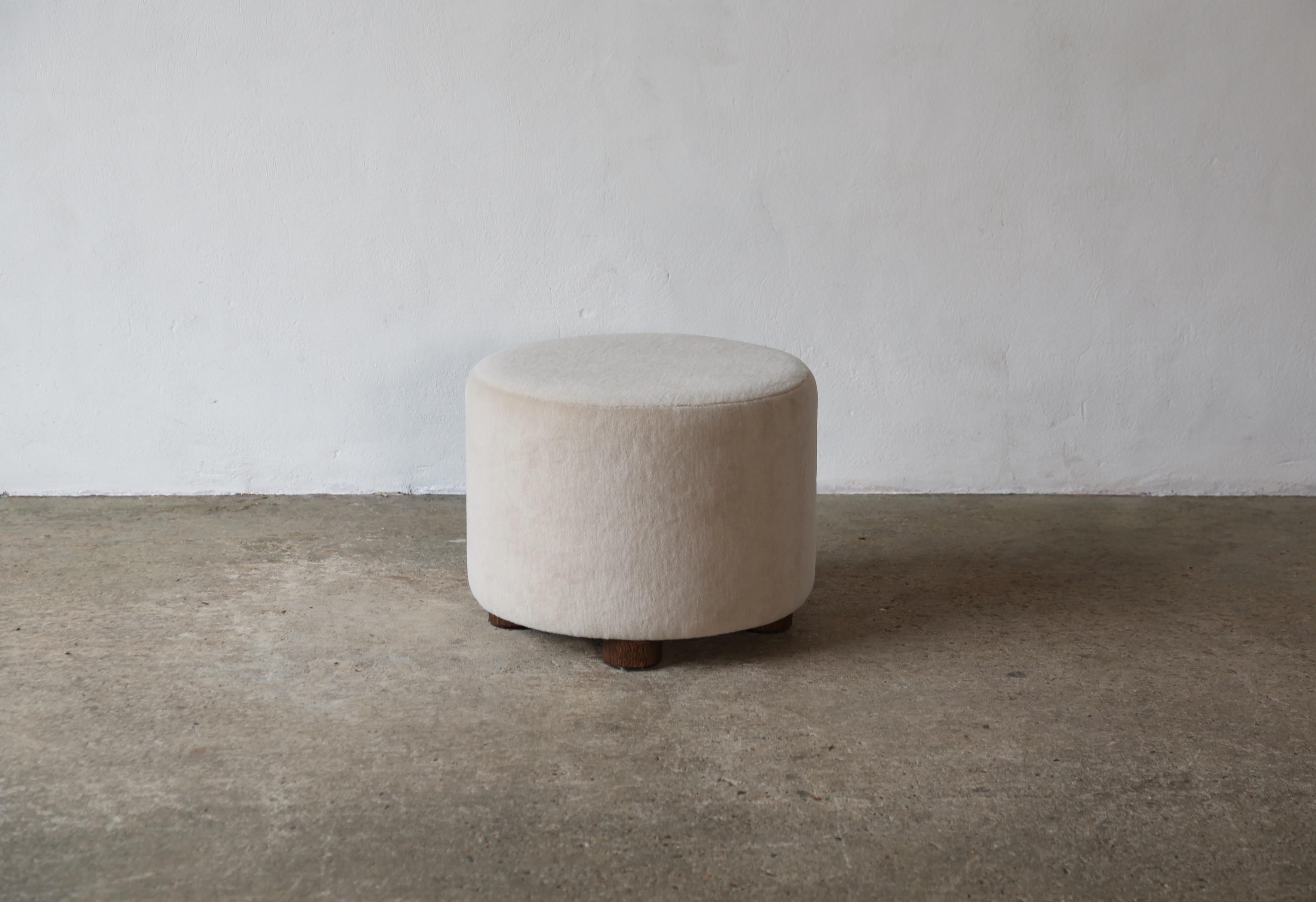 Un ottoman élégant, moderne, bas et rond.  Fabriqué à la main en Angleterre.  Nouvellement revêtu d'un tissu en pure laine d'alpaga de première qualité et doux, avec des pieds en chêne massif.    Des tailles et des tissus sur mesure sont