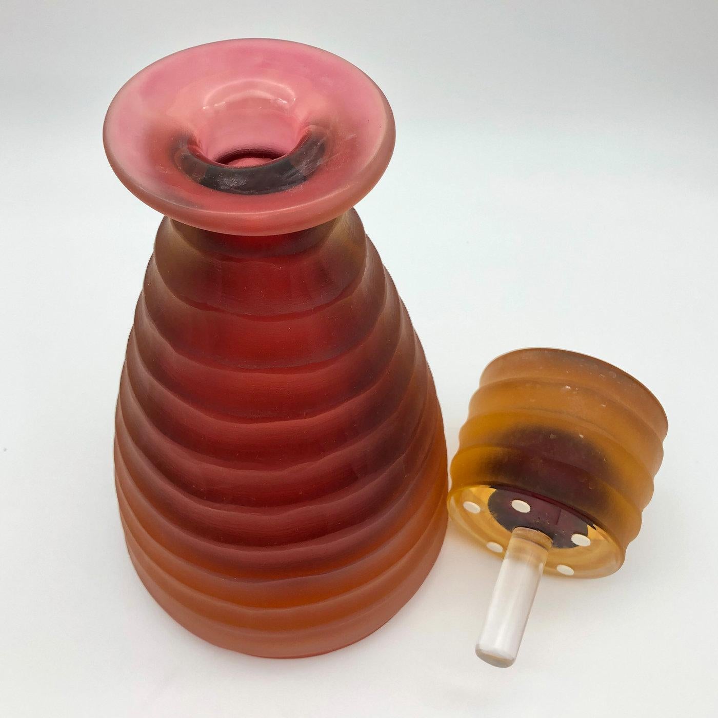 Distinguished by an alluring combination of warm amber and ruby hues, this exceptional bottle will add an accent of color and a singular charm to any dining table. Meticulously handcrafted and carved by hand by Ars Murano's master glassmaker Achille