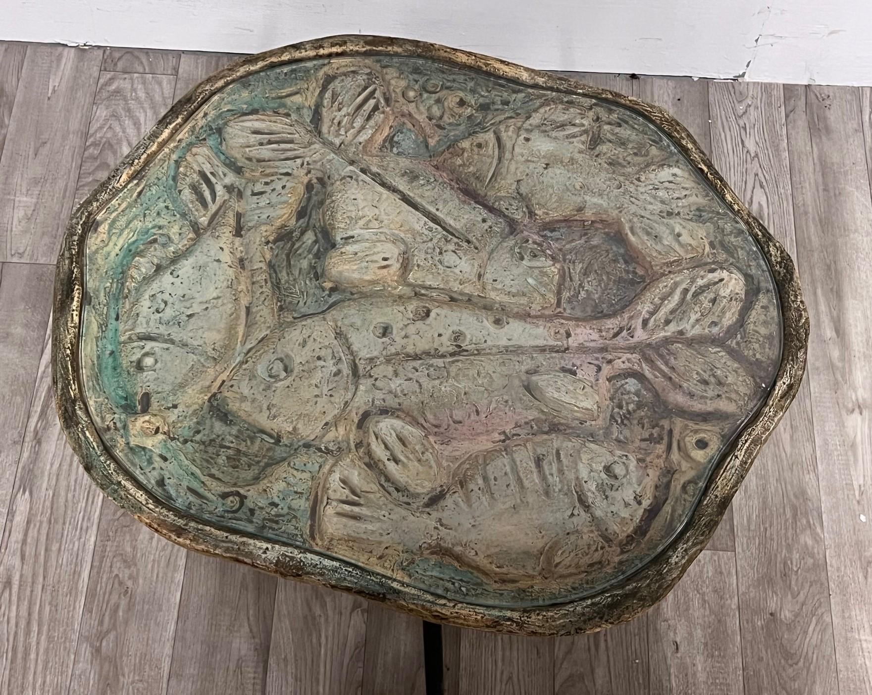 Un tavolo molto particolare con un disegno di un pesce strutturato sotto un pezzo di vetro. 
Sembra un'opera d'arte. 