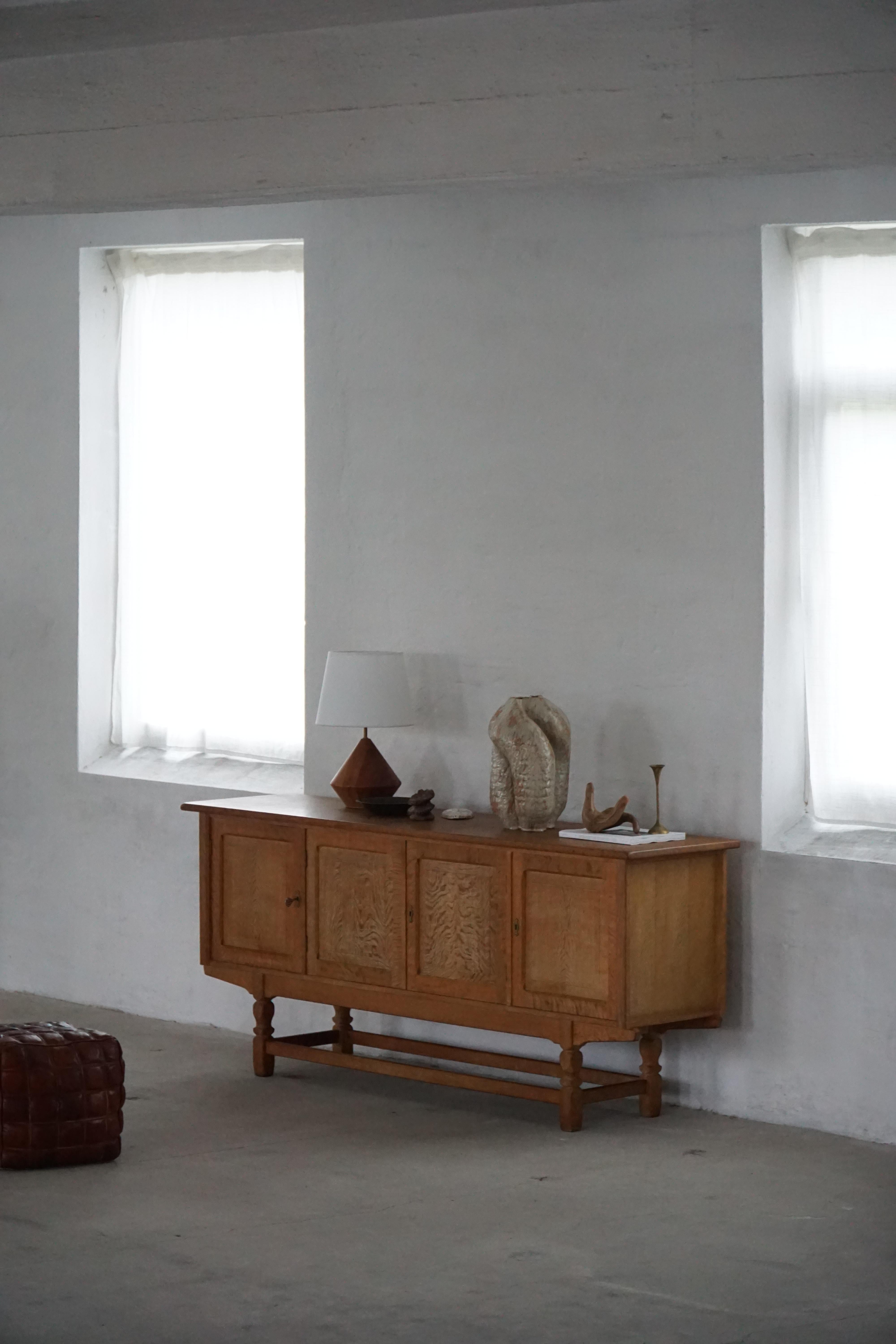 A sculptural low rectangular classic sideboard / cabinet in oak with plenty of storage and a beautiful carved front design. Made by a Danish cabinetmaker in the 1960s. 
Four doors, inside storage and drawers.

This nice brutalist sideboard will
