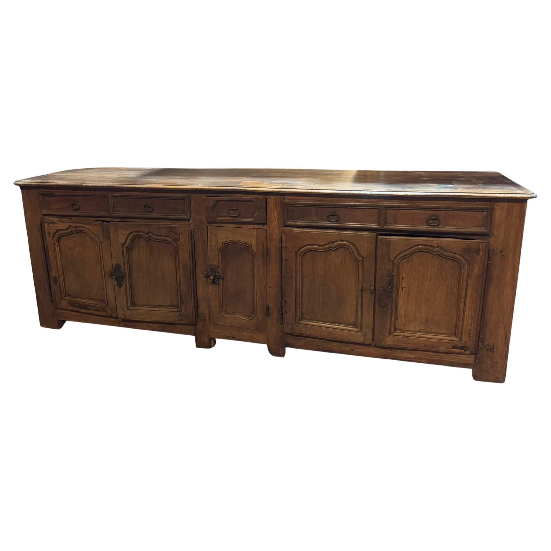 Buffet ancien en noyer massif, long avec cinq portes avec panneaux sculptés et cinq tiroirs. Beau buffet bas patiné, avec panneaux sculptés ondulés, intérieur avec étagères, original du 18ème siècle, originaire de France.
Dimensions maximales cm L