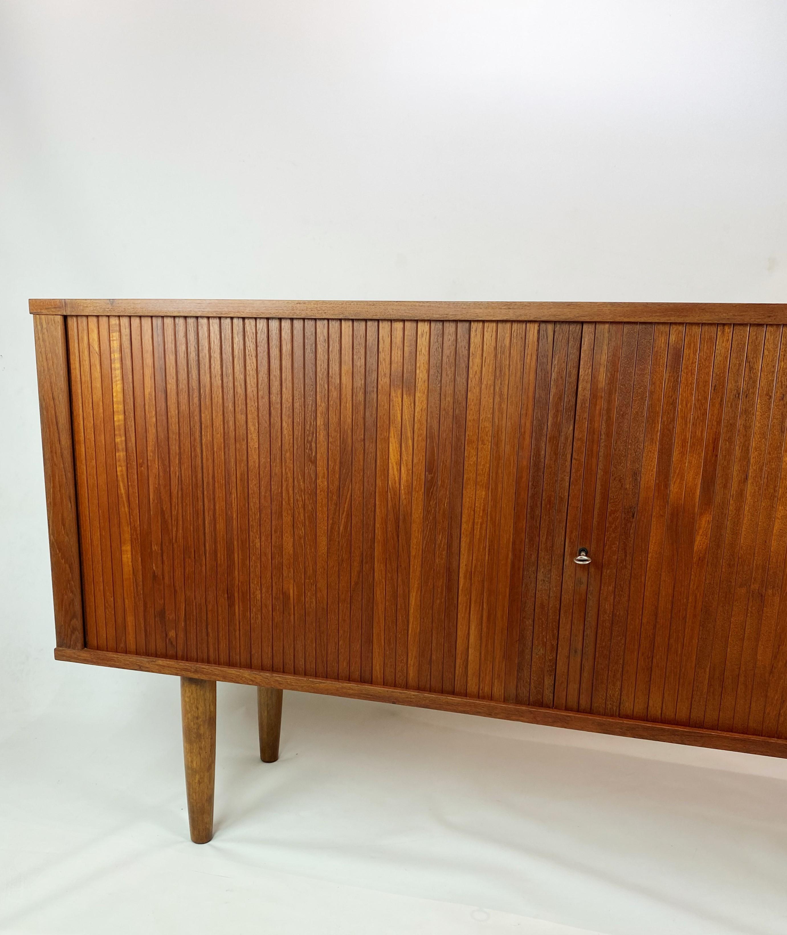 Low sideboard with sliding doors in teak of Danish design from the 1960s. The sideboard is in great vintage condition.
 