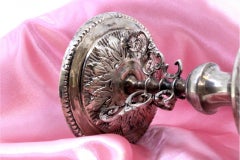 Low silver candlestick with relief engravings on round base with three legs