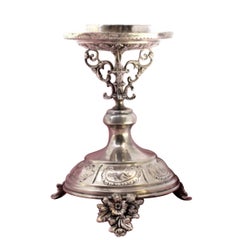 Low silver candlestick with relief engravings on round base with three legs