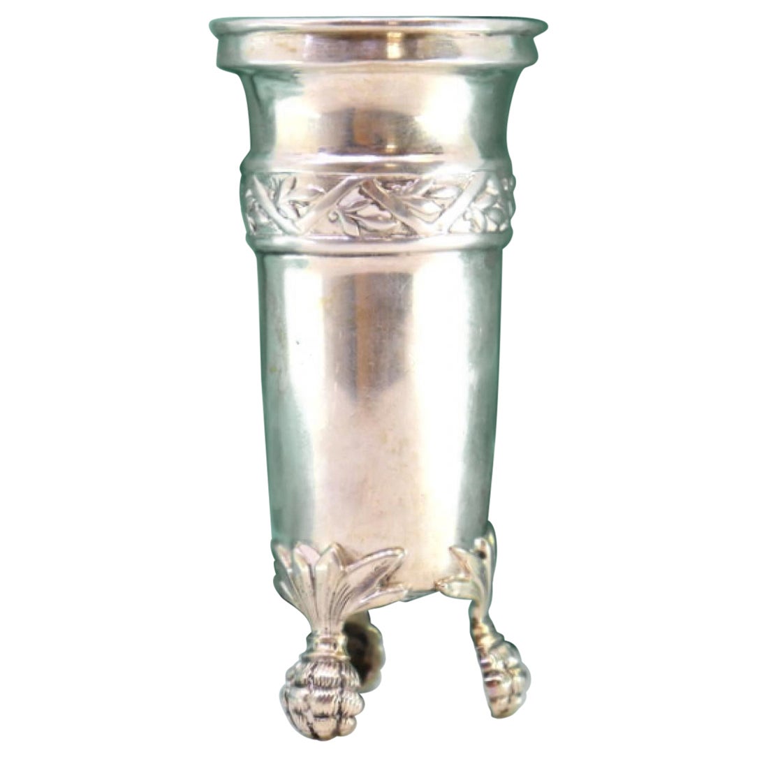 Low silver candlestick with reliefs and resting on three claw-shaped feet
