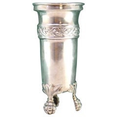 Low silver candlestick with reliefs and resting on three claw-shaped feet