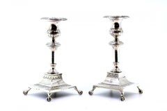 Low silver candlesticks with engraved shafts and four claw-shaped feet