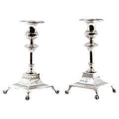 Low silver candlesticks with engraved shafts and four claw-shaped feet