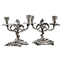 Low silver two-light candelabra with shells, garlands and cut-out bases Low silver two-light candelabra with shells, garlands and cut-out bases