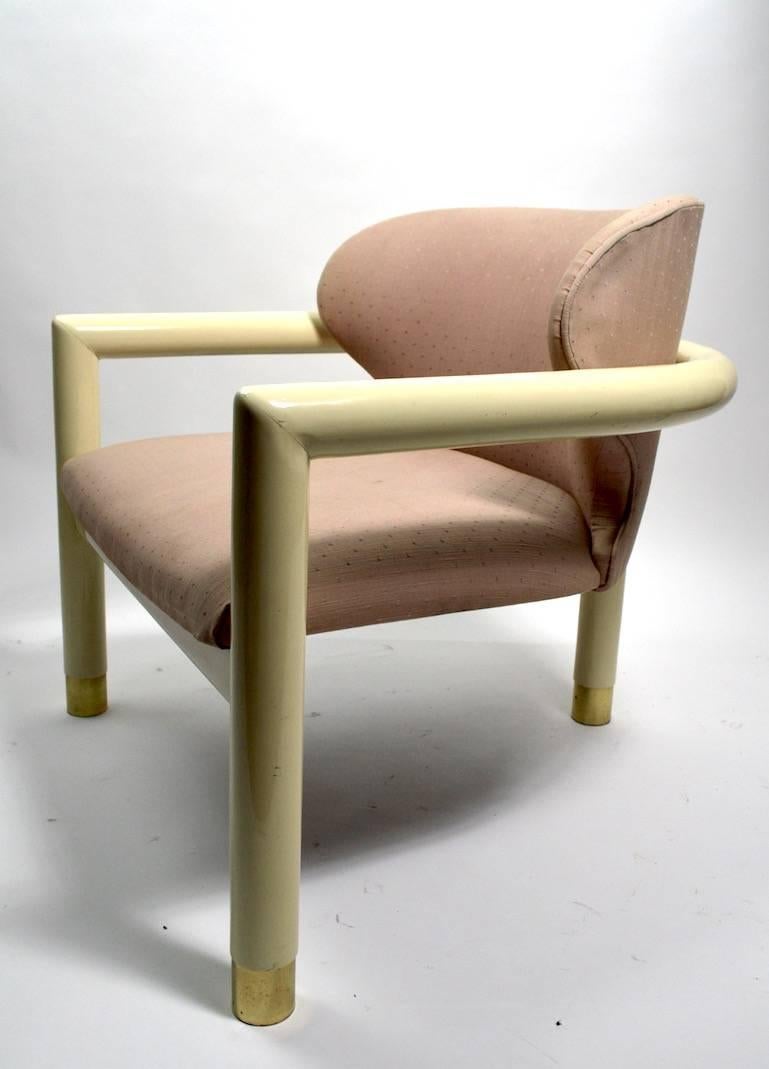 Great Art Deco Revival low slung lounge chair with cream lacquer frame, brass feet, and upholstered seat and back. The chair is in very good condition, showing only light cosmetic wear, normal and consistent with age, with exception of the fabric
