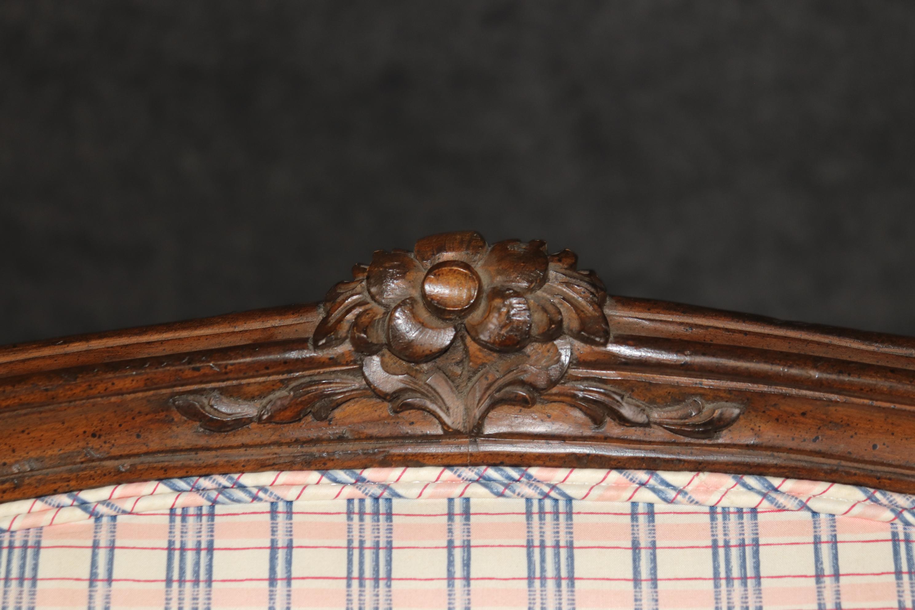 Voici une superbe paire de chaises bergère en noyer sculpté de style Louis XV. Les chaises sont en bon état d'origine, avec une charmante tapisserie à carreaux roses et bleus et de superbes cadres sculptés à la main avec des fleurs et des genoux