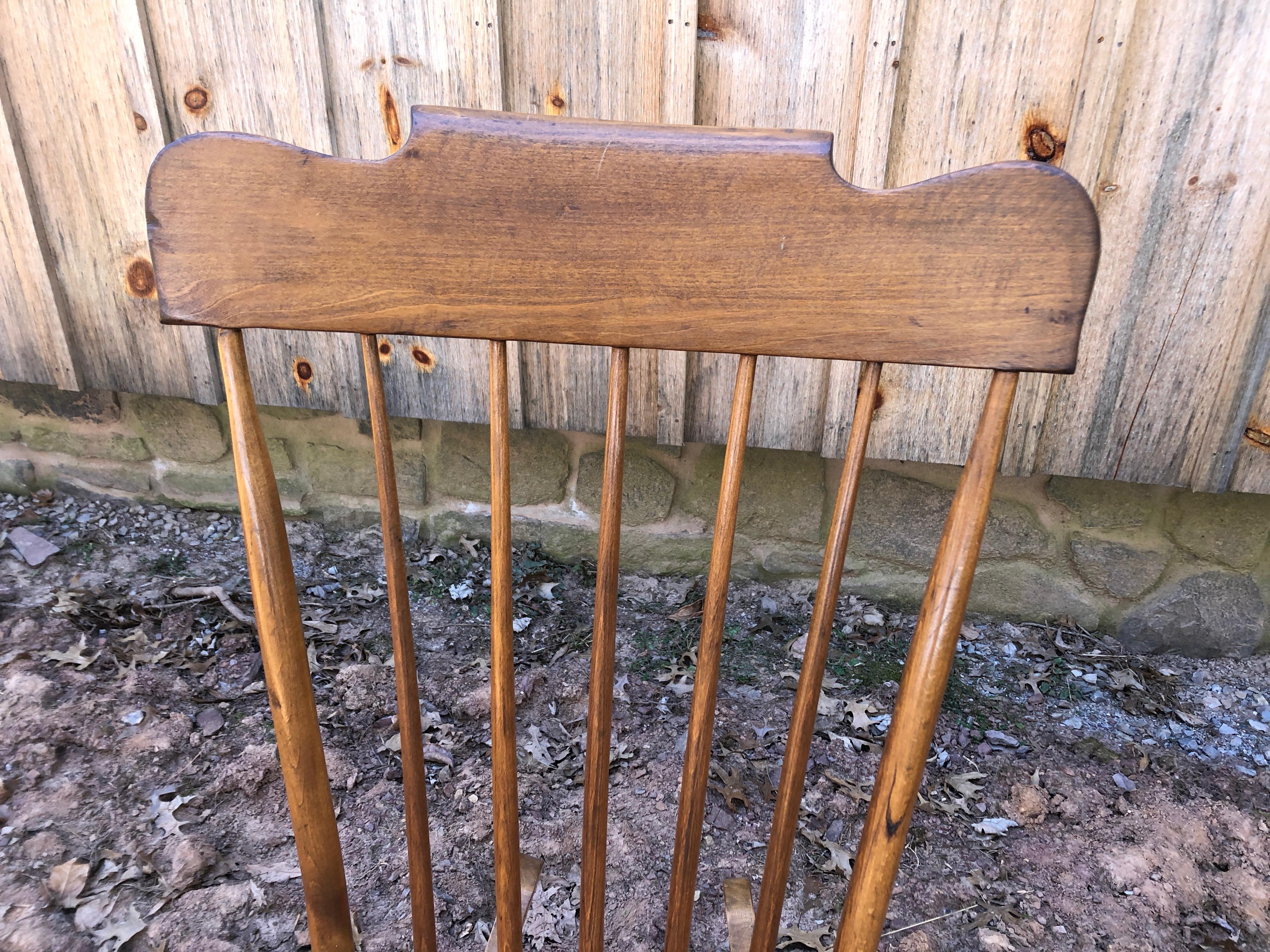 Vintage handmade wooden rocking chair, low to the ground, having a slab seat and elongated spindle back.