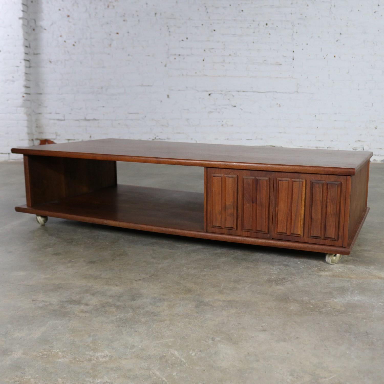 Handsome midcentury low-slung rolling coffee table with partial see thru open shelf and doored storage cabinet on brass ball casters. It is in fantastic vintage condition with no outstanding flaws we have detected. Unmarked circa 1960s-1970s.

If