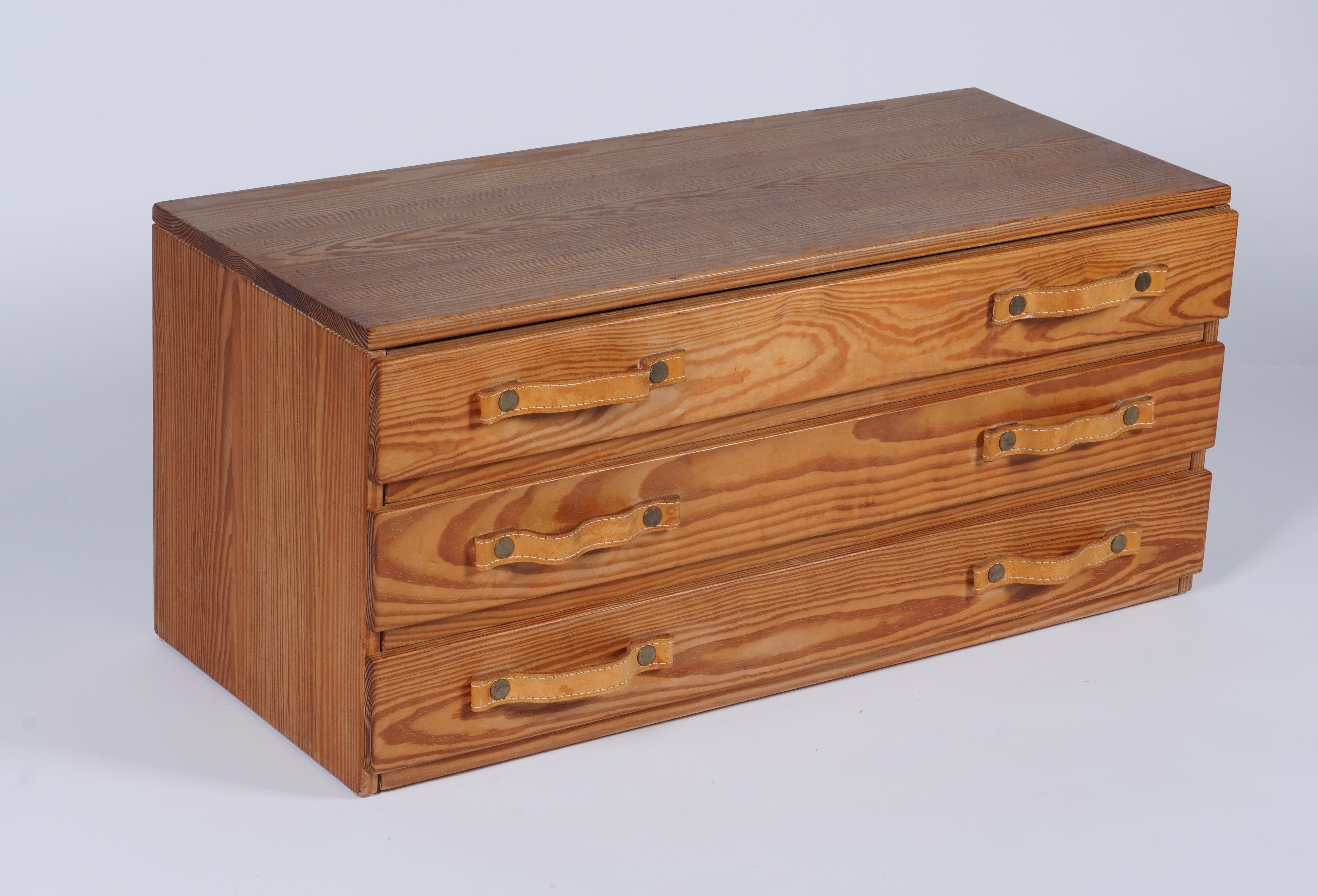 Cassettiera bassa proveniente dalla Svezia e importata dalla Danimarca, costruita in pino con venature espressive, tiranti in pelle e ferramenta in ottone. Composto da 3 ampi cassetti con un profilo elegante, è fantastico per riporre oggetti extra