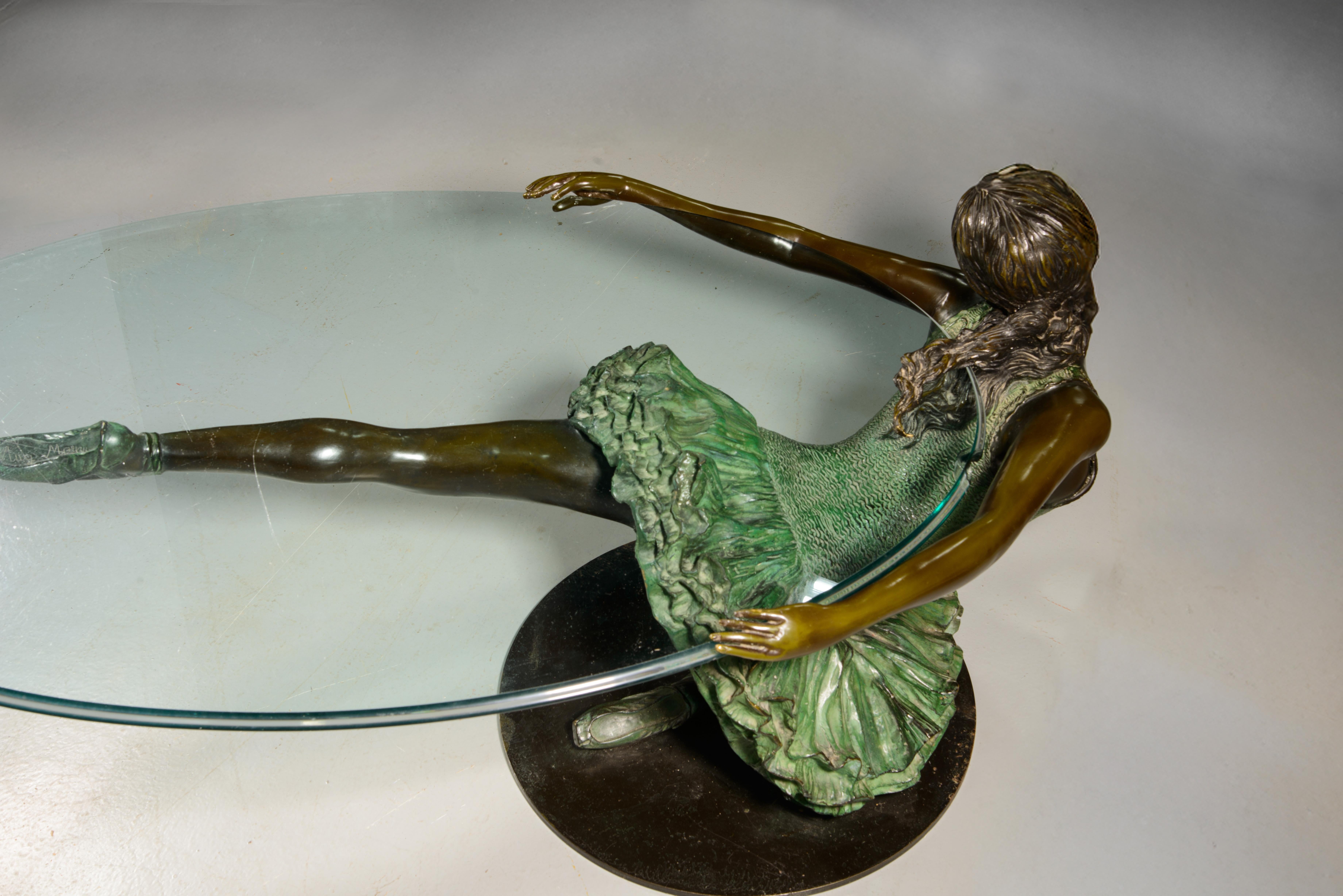  Niedriger Tisch, Tänzer. Bronze, Glas. 20. Jahrhundert. 
Glasfehler. 
Niedriger Tisch mit durchsichtiger ovaler Glasplatte, auf der eine weibliche Bronzefigur einer Tänzerin in tänzerischer Pose steht. Die Figur ist inspiriert von den Vorbildern