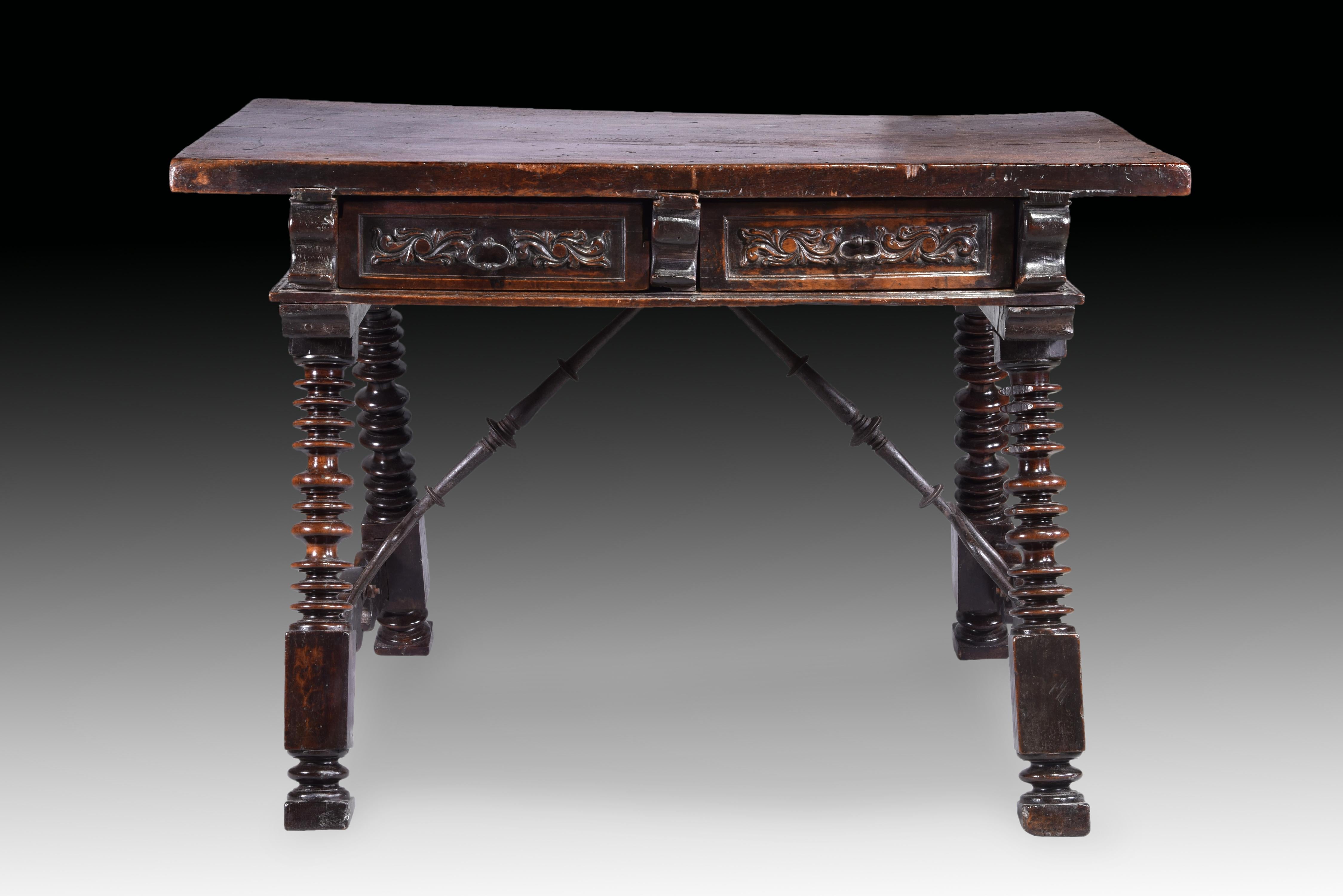 table with hairpin clips. Walnut wood, wrought iron. Spain, 17th century.
 table made of carved and turned walnut wood with four A-legs, two wrought iron hairpin clips and drawers on both fronts (a total of four) decorated with plant-themed