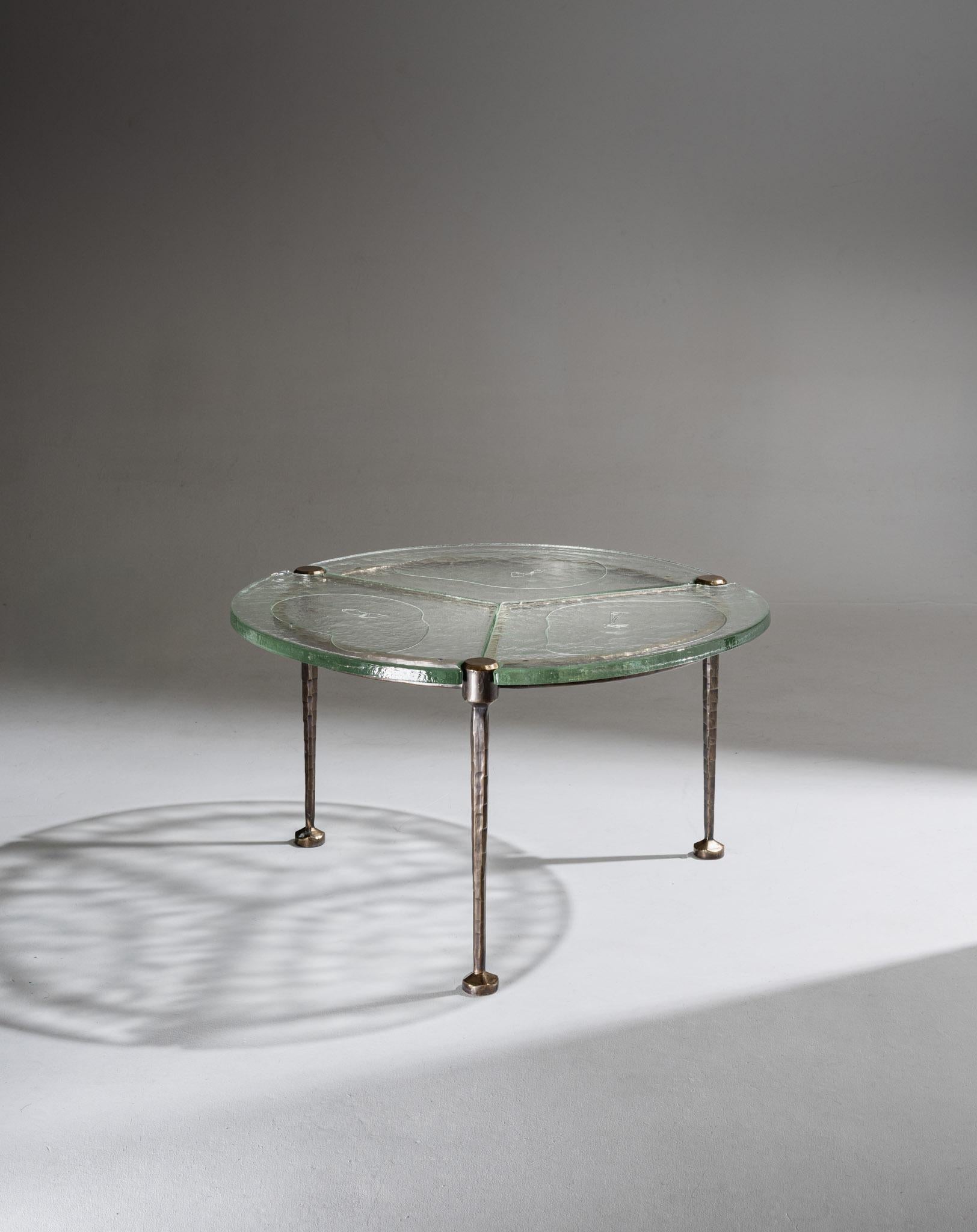 Brutalist low table by German artist Lothar Klute, made in the 1980s.
The circular tabletop in thick, textured, and slightly bubbled glass is divided into three sections and can be detached from the structure. It rests on a base with four slender