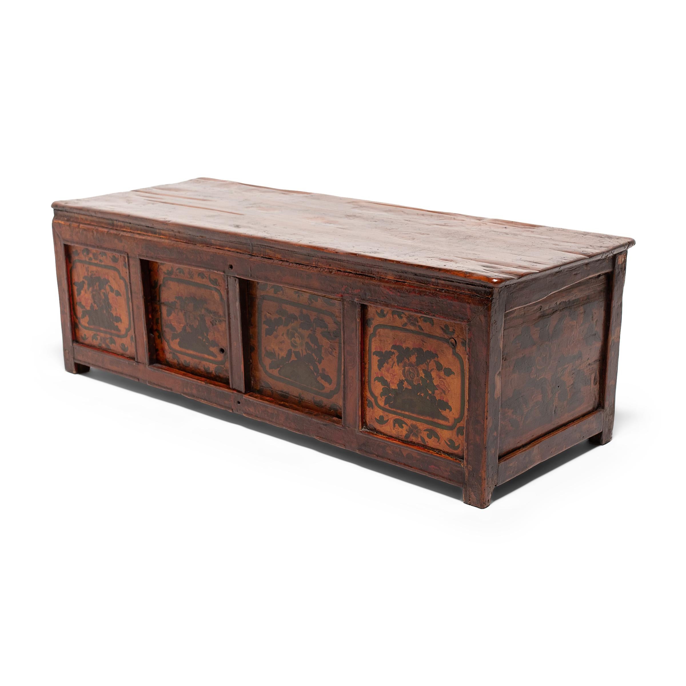 This early 20th century Tibetan painted cabinet would have originally been used atop a kang or platform bed, used as a table and storage chest. The low cabinet has a simple rectangular design with short legs, inset paneled sides, and a slightly