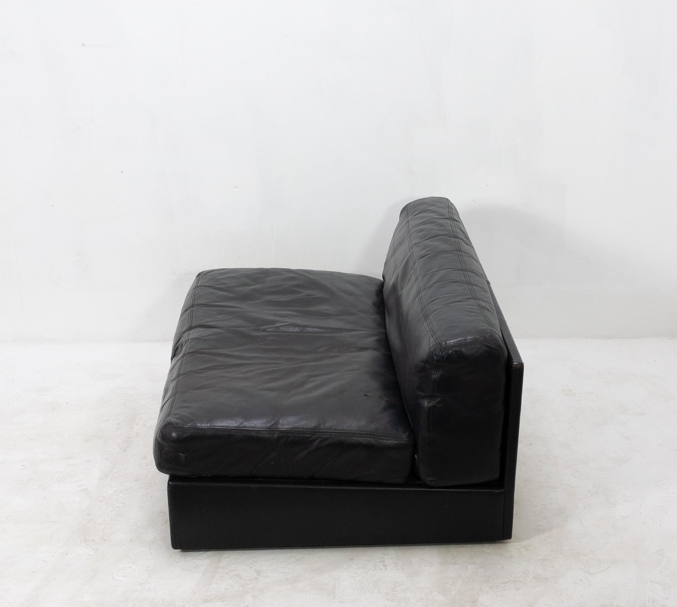 Handsomely distressed low-slung black leather sofa or loveseat from the 1960s. In the style of De Sede and featuring very nice quality materials.