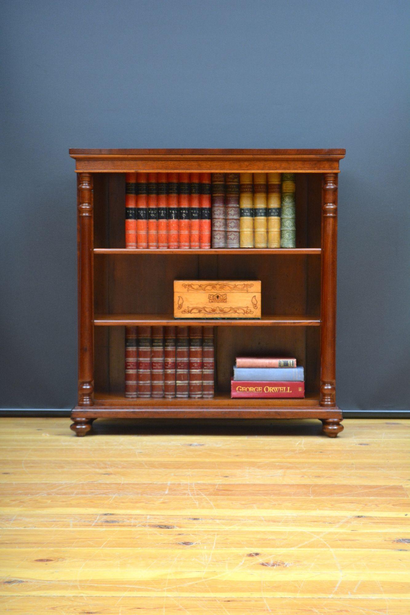 Sn5650 English antique, mahogany open bookcase, having figured mahogany top above a shallow frieze and two height adjustable shelves, all flanked by turned columns with shaped capitals, standing on original bun feet. This antique bookcase has been