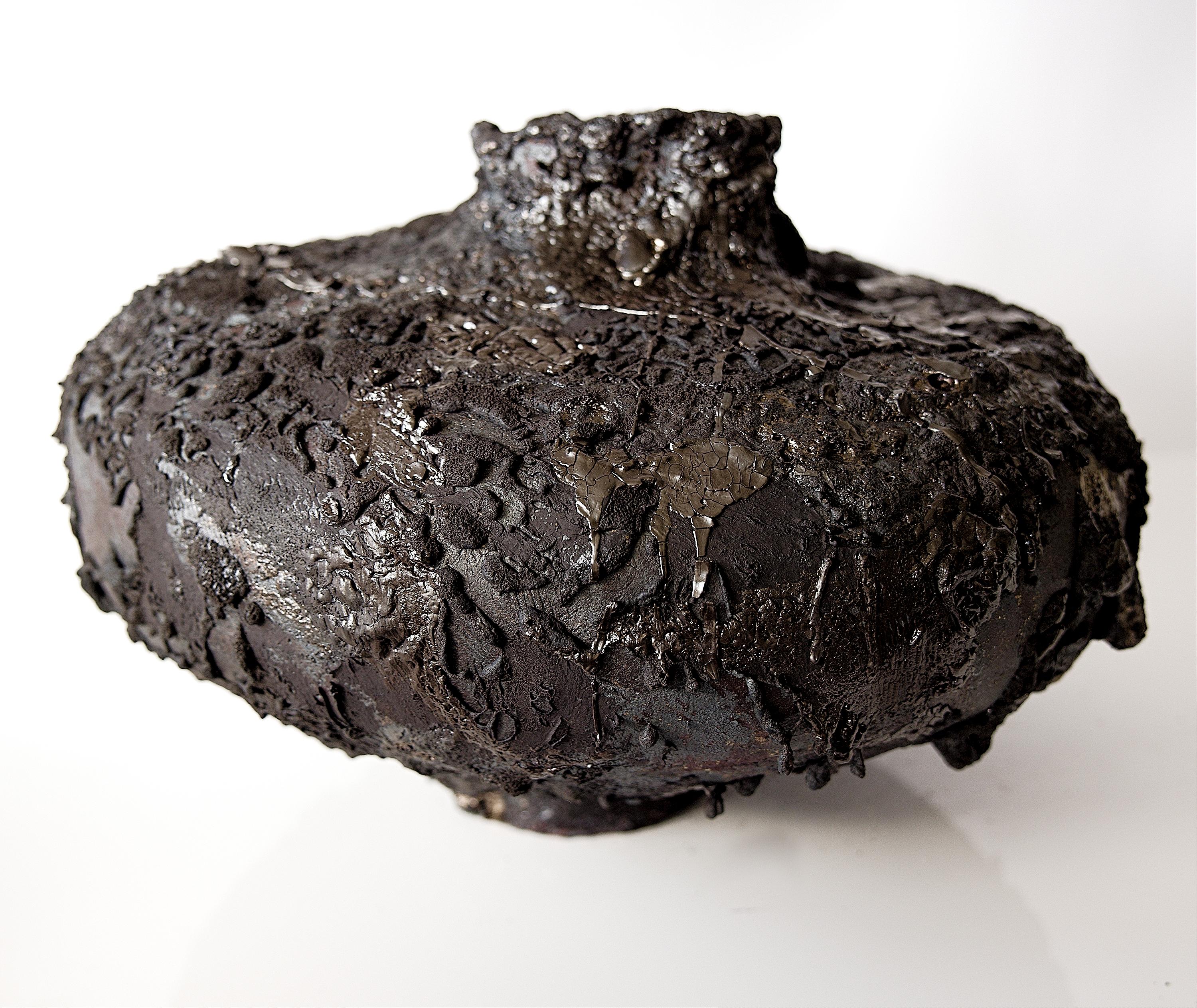 Ti presentiamo il Moody Lava Moon Collector, disponibile in esclusiva presso gli Studio A. Questo grande vaso arrotolato a mano presenta una finitura opaca con strati di argilla pesante e barbottina e un'aggiunta di smalto lavico, incarnando la