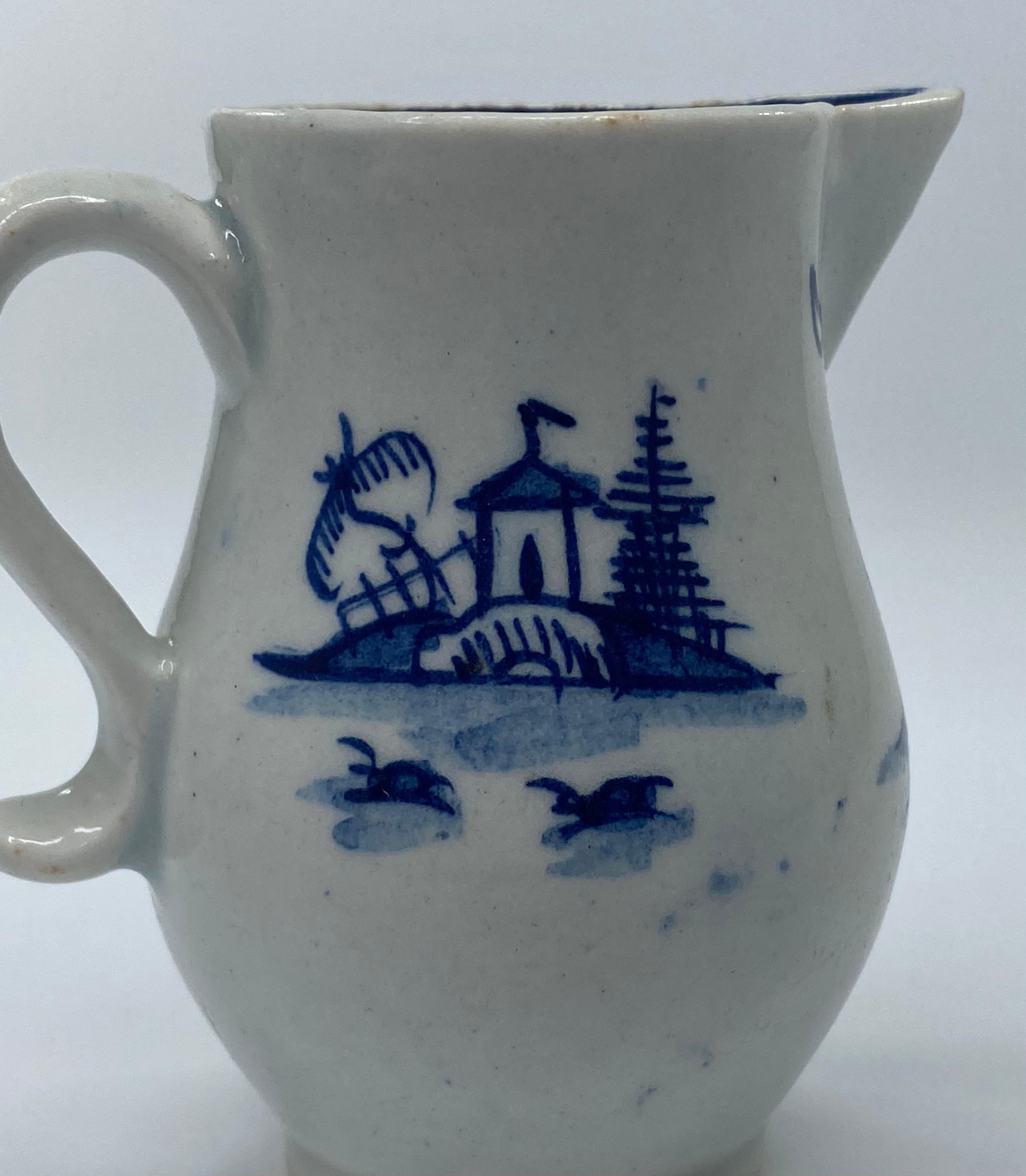 Lowestoft Porcelain sparrow beak jug, c. 1765. The bellied jug, painted in underglaze blue, with Chinese buildings on islands, in a river. The interior rim, painted with stylised flowering branches, between a chevron motif.
Measures: Height: 7.7