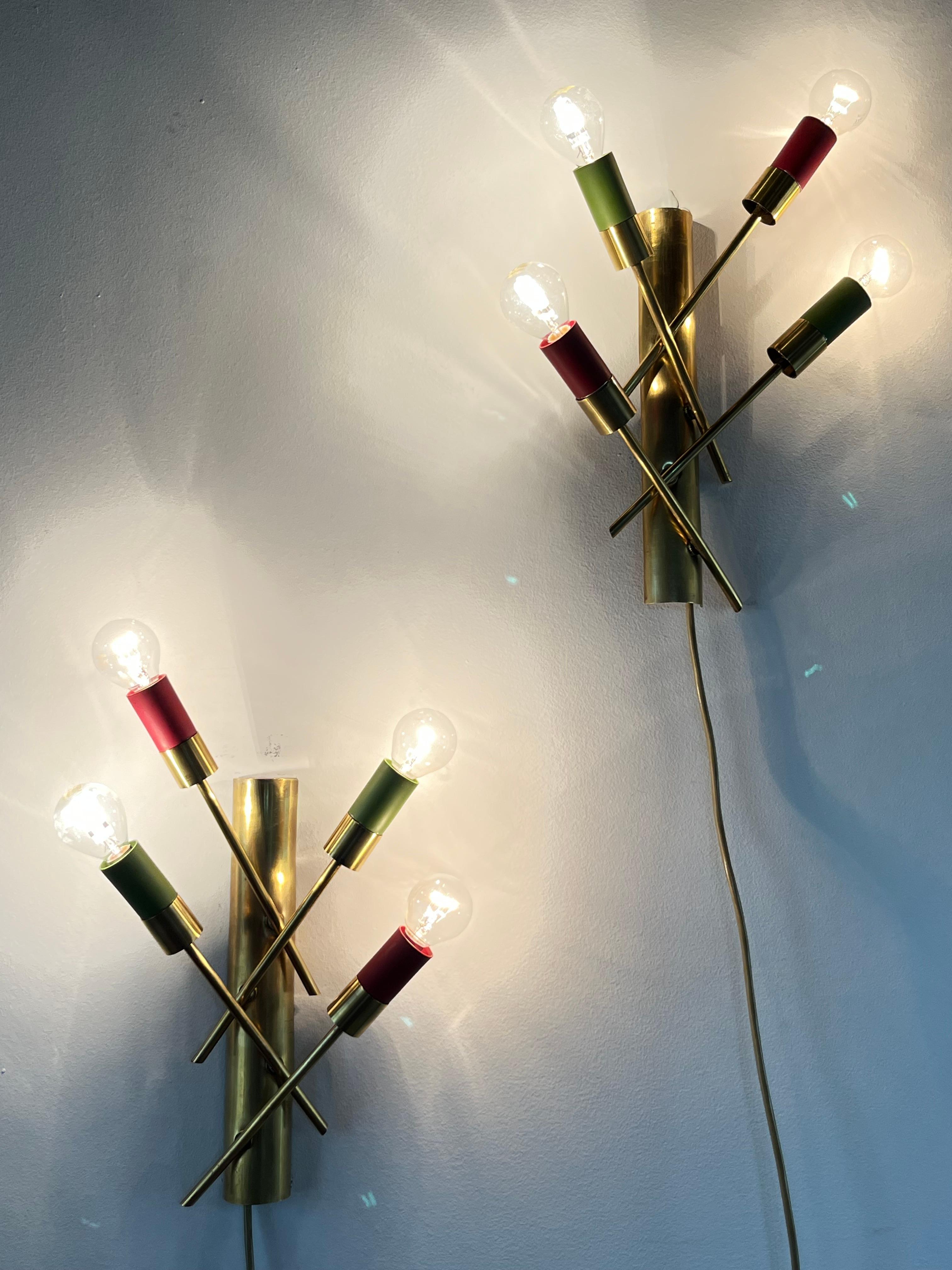 Seltenes Paar Wandlampen aus Messing, 1950er Jahre mit 4 Lichtern, italienische Produktion. Konkave Sockel mit jeweils vier schrägen Stäben, die auf Wunsch verbreitert oder verengt werden können.
Die Lampenfassungen sind aus Aluminium, 4 grün