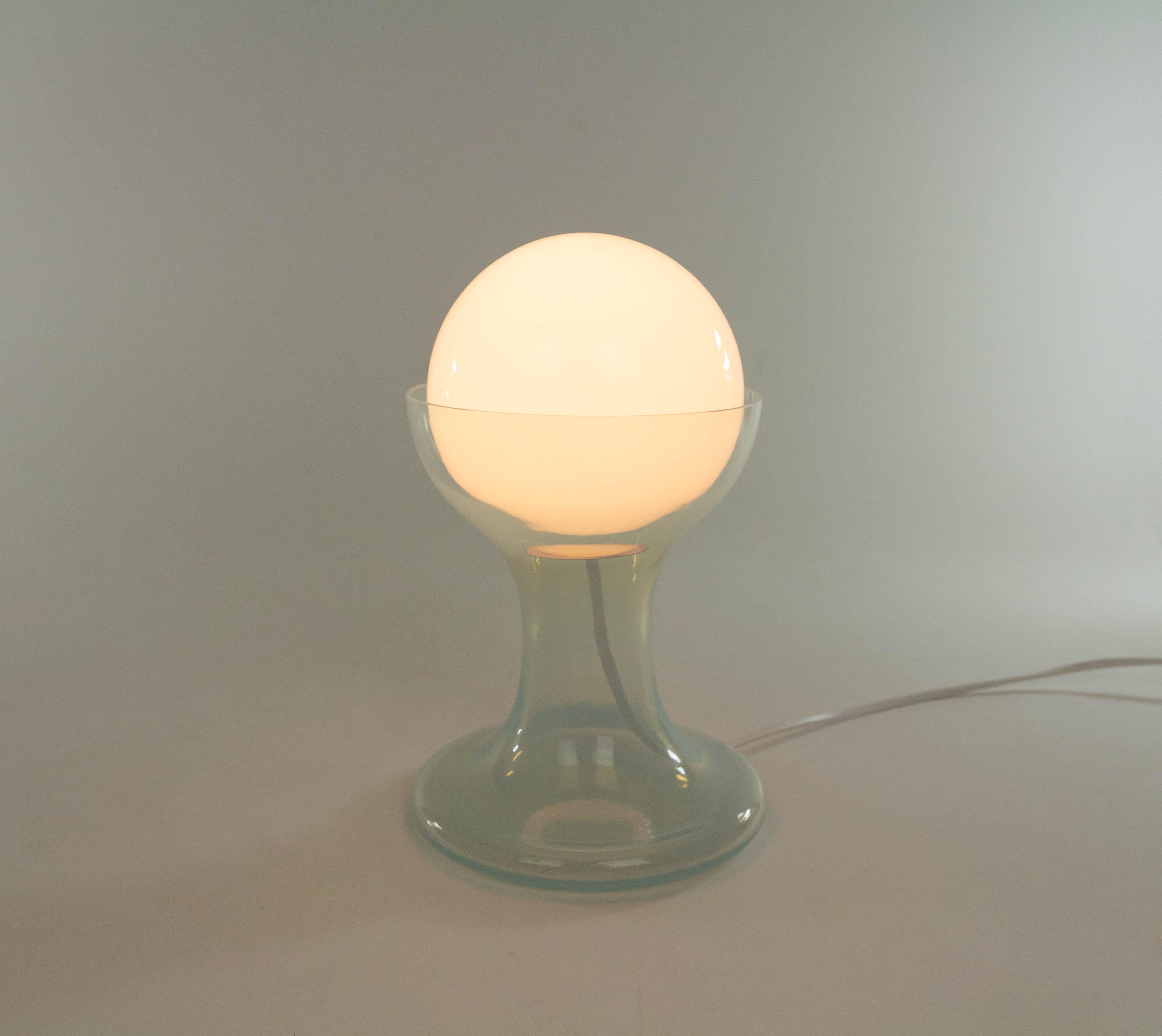 Lampe de table LT 215 conçue par Carlo Nason et fabriquée dans les années 1960 par le verrier Murano A.V. Mazzega. La lampe est composée d'un globe en verre blanc et d'une base en verre de Murano.

Ce modèle a été produit en deux tailles ; il s'agit