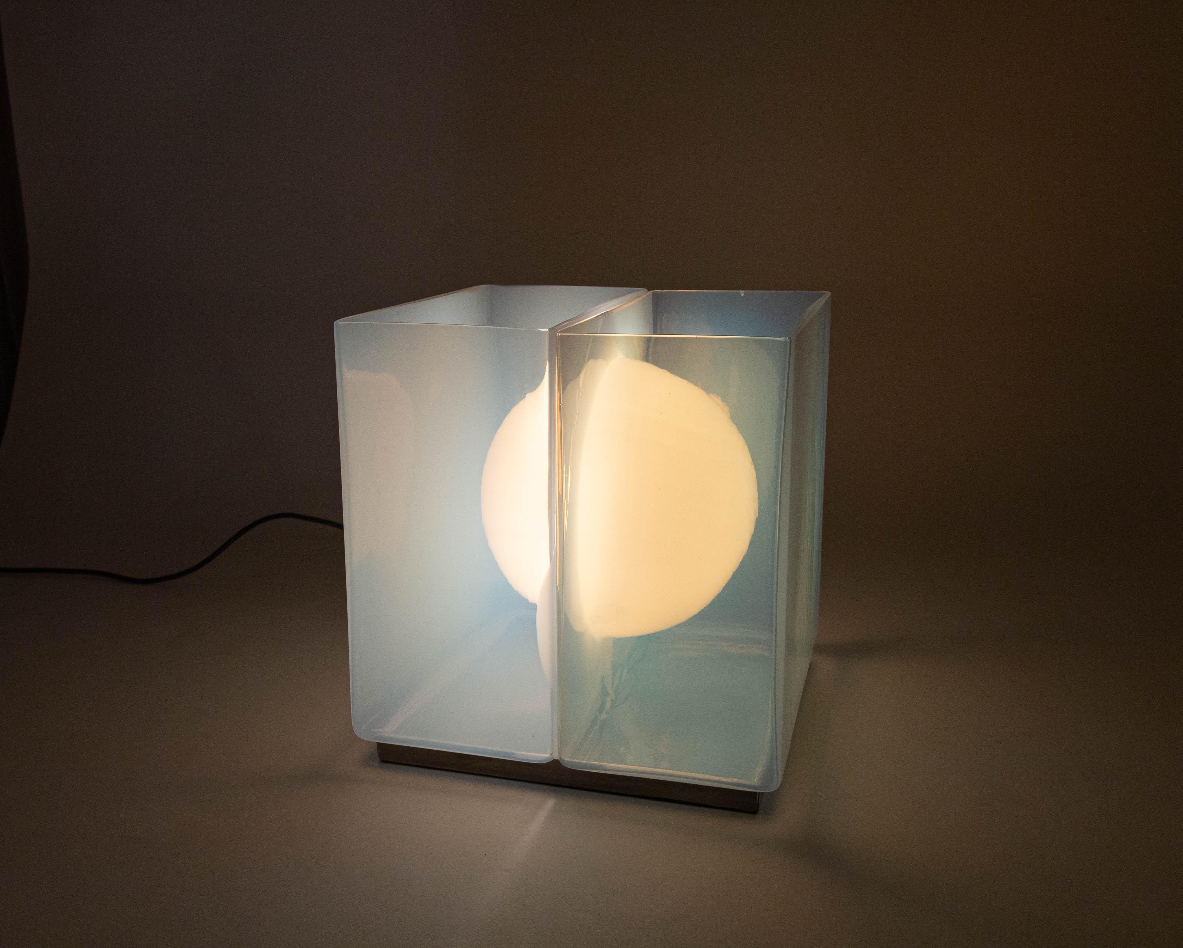 Model LT 323 Table lamp designed by Carlo Nason and manufactured by A.V. Mazzega in the 1960s.

The ingenious hand blown- object consists of two symmetrical opaline glass halves, one central light bulb and a square metal support base. The halves are