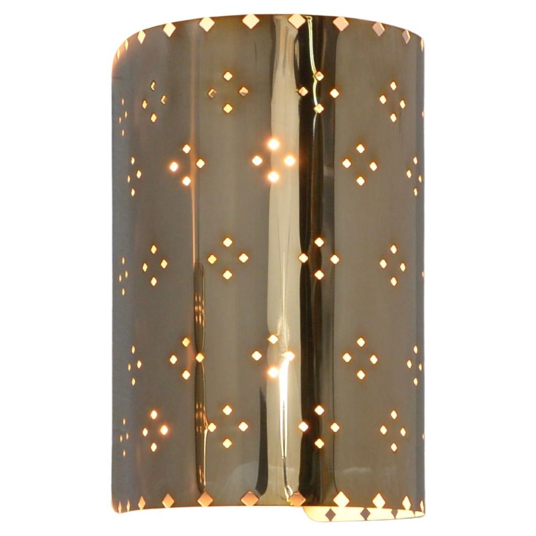 El atractivo aplique LU Louis SM es una versión más pequeña de nuestro aplique LU Louis, un aplique de pared totalmente de latón en acabado plateado envejecido con perforaciones estampadas de Lumfardo Luminaires. De fabricación contemporánea en