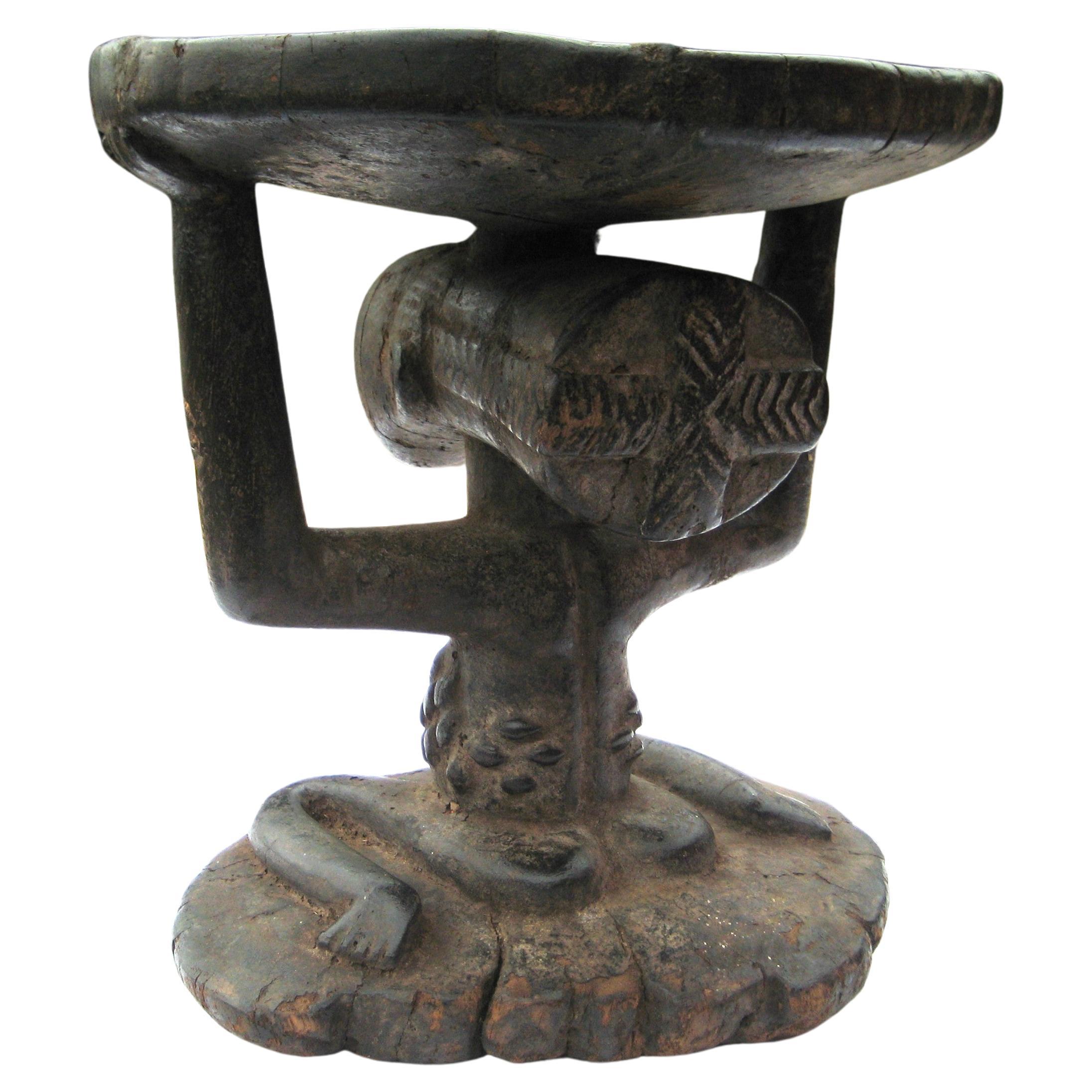 Antico sgabello del popolo Luba scolpito a mano da un unico pezzo di legno con figura ancestrale femminile cariatide come supporto centrale. Presenta buoni segni dell'età e un bel colore antico della superficie. Repubblica Democratica del Congo.