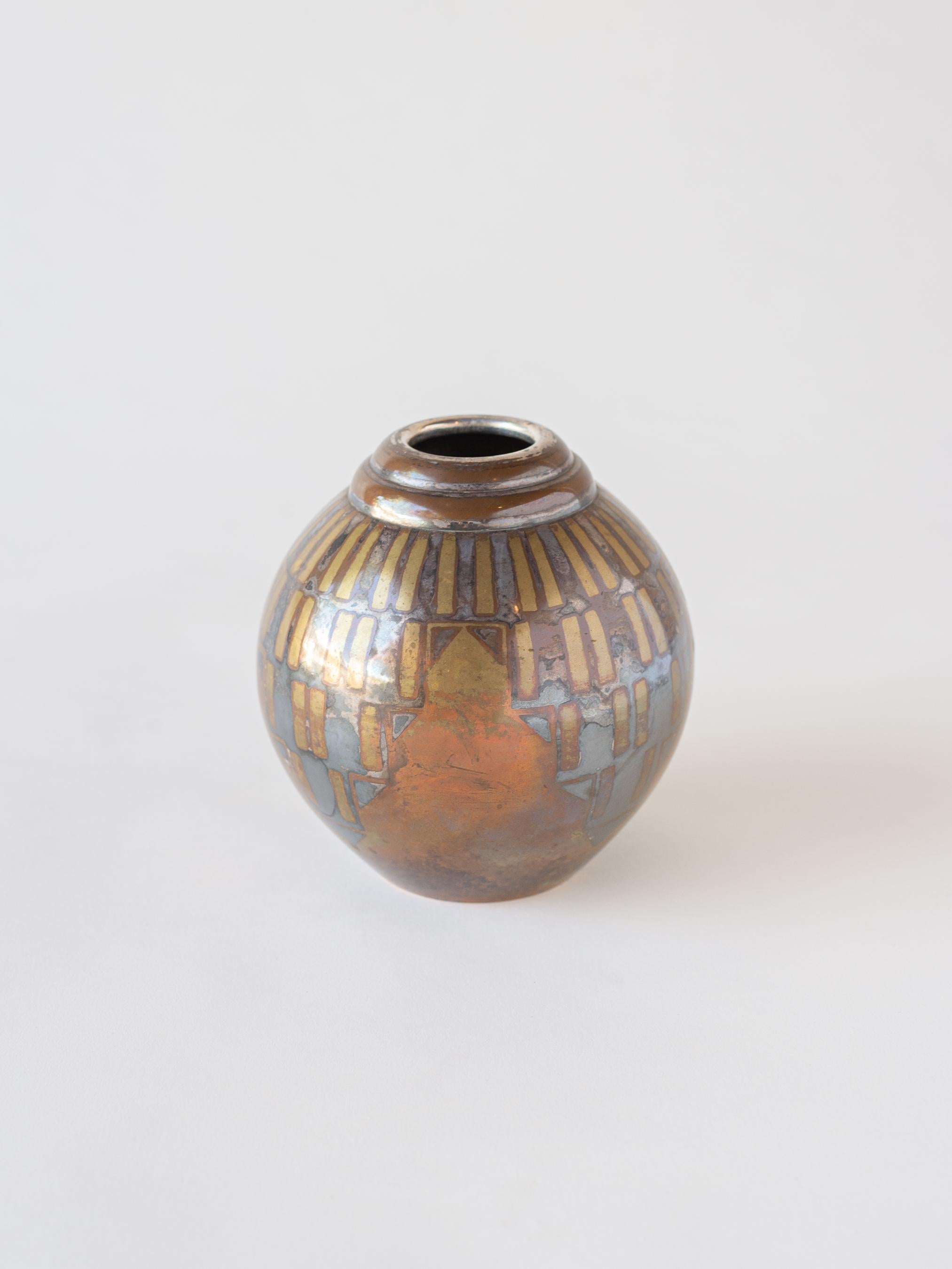 A French Art Deco vase with ovoid body and stepped lip. A heavily patinated geometric design in various metals including copper, brass, and silver decorate the body. A design by Luc Lanel (1893-1965) produced by Christofle Paris in the 1930s.