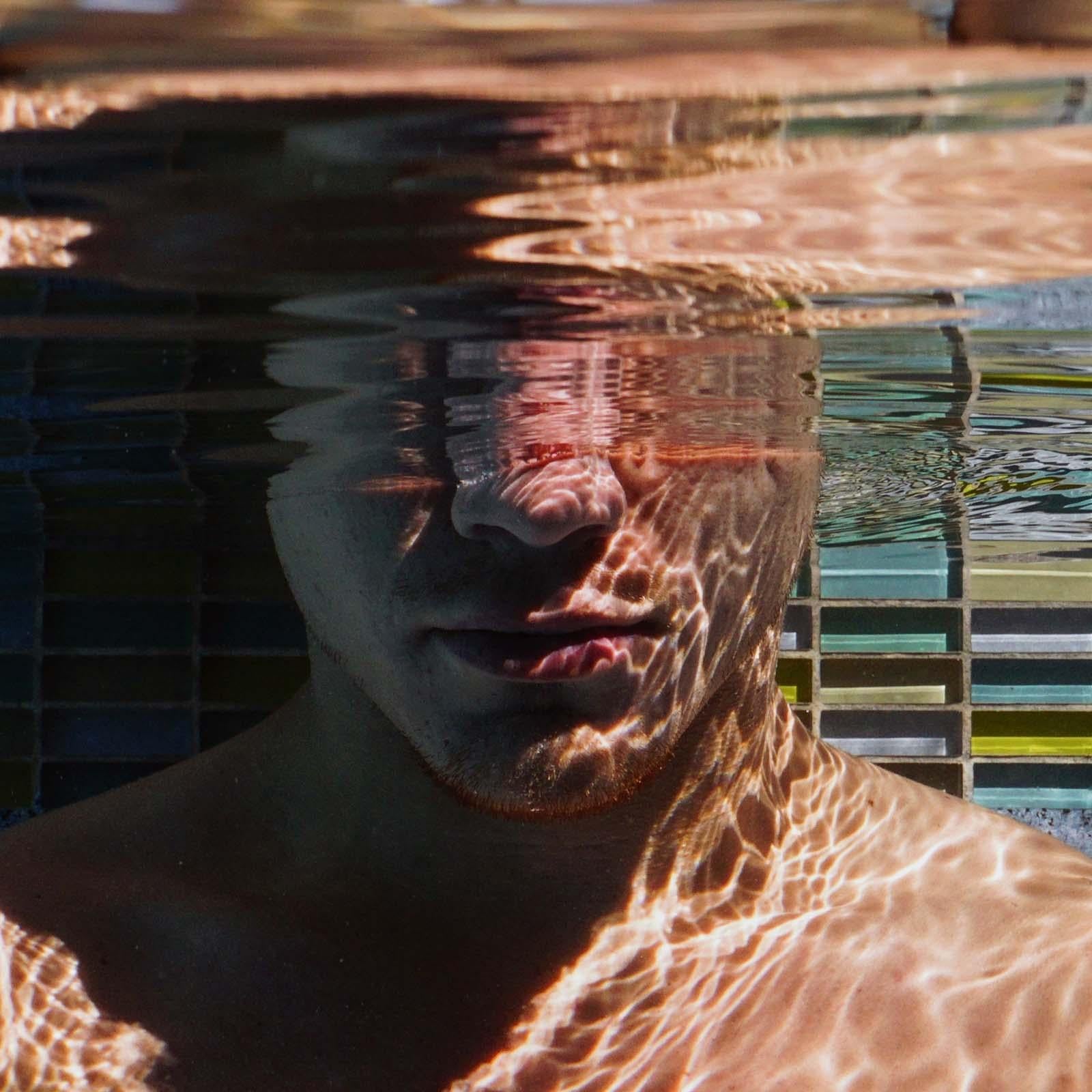 Mente sobre Materia (Joven buceador masculino prueba el control de la respiración salpicado por el sol  piscina) - Photograph de Lucas Murnaghan