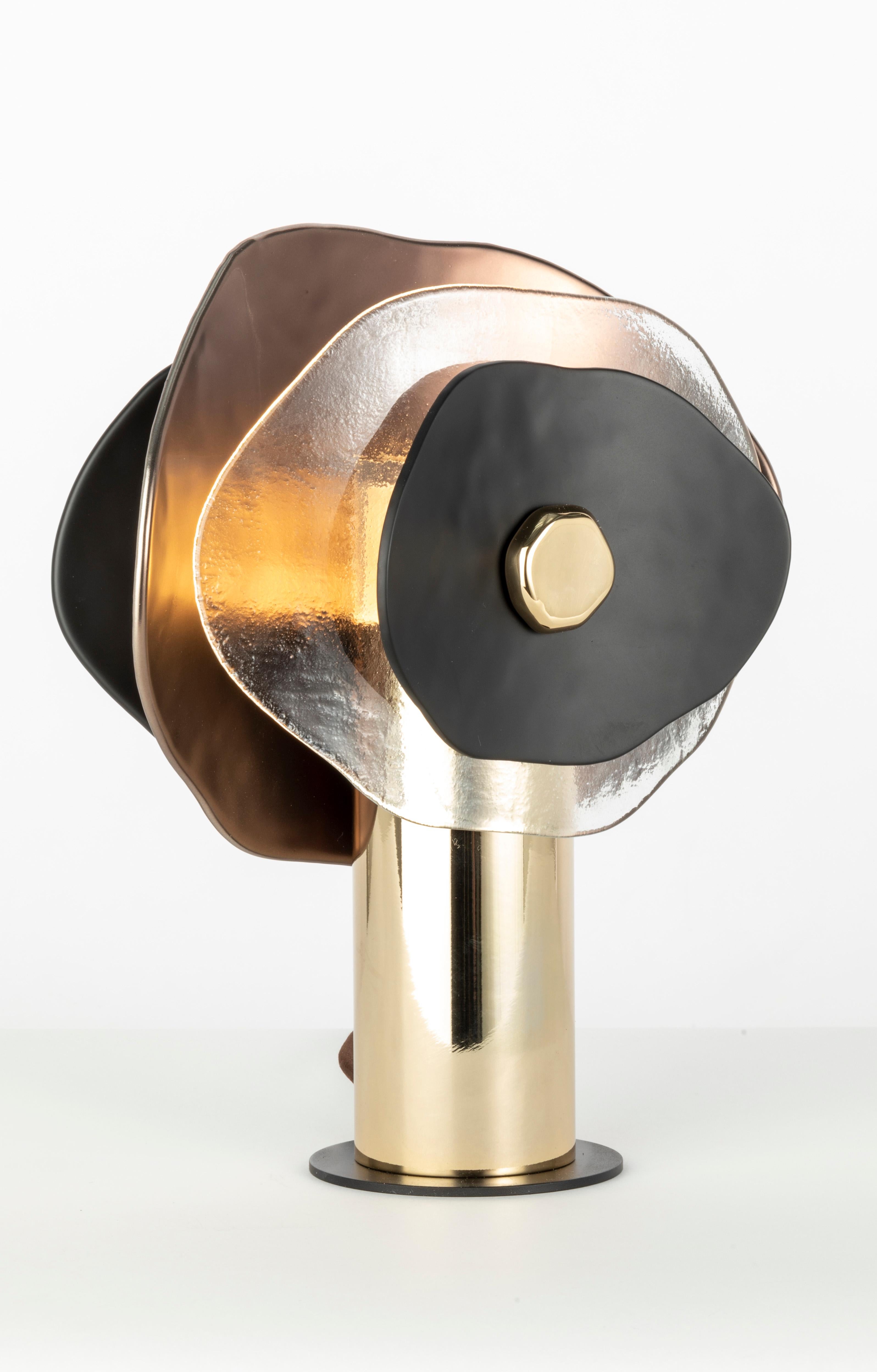Lampada da tavolo piccola. Composizione di petali in vetro trasparente, finitura bronzo semilucido e nero matte. Minuteria metallica in oro chiaro lucido; cavo di seta marrone. Una luce centrale; diffusore in vetro satinato e copertura in