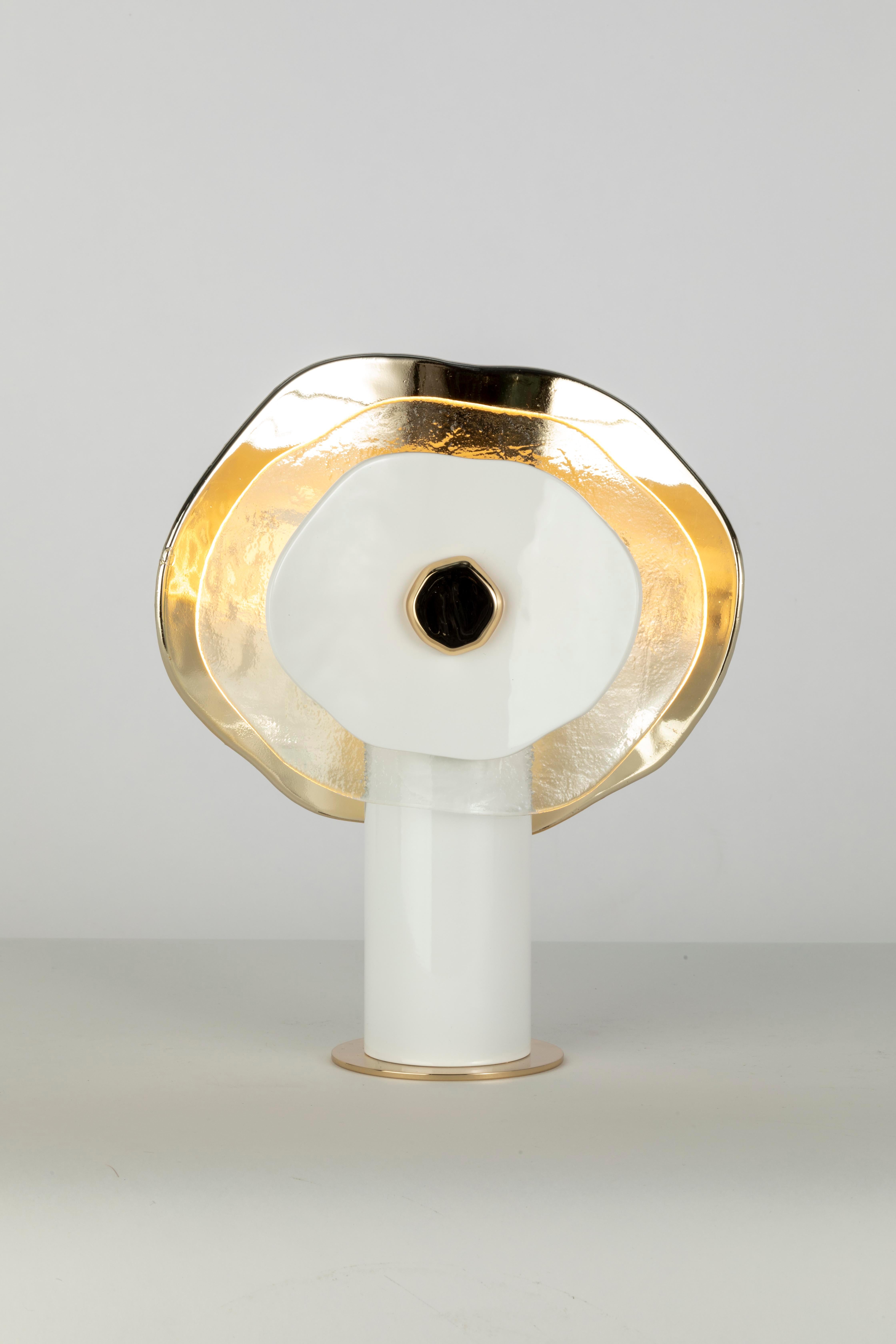 Lampada da tavolo piccola. Composizione di petali in vetro trasparente, finitura oro chiaro lucido e bianco. Minuteria metallica coordinata; cavo di seta avorio. Una luce centrale; diffusore in vetro satinato e copertura in plexiglass.
Disegnato da