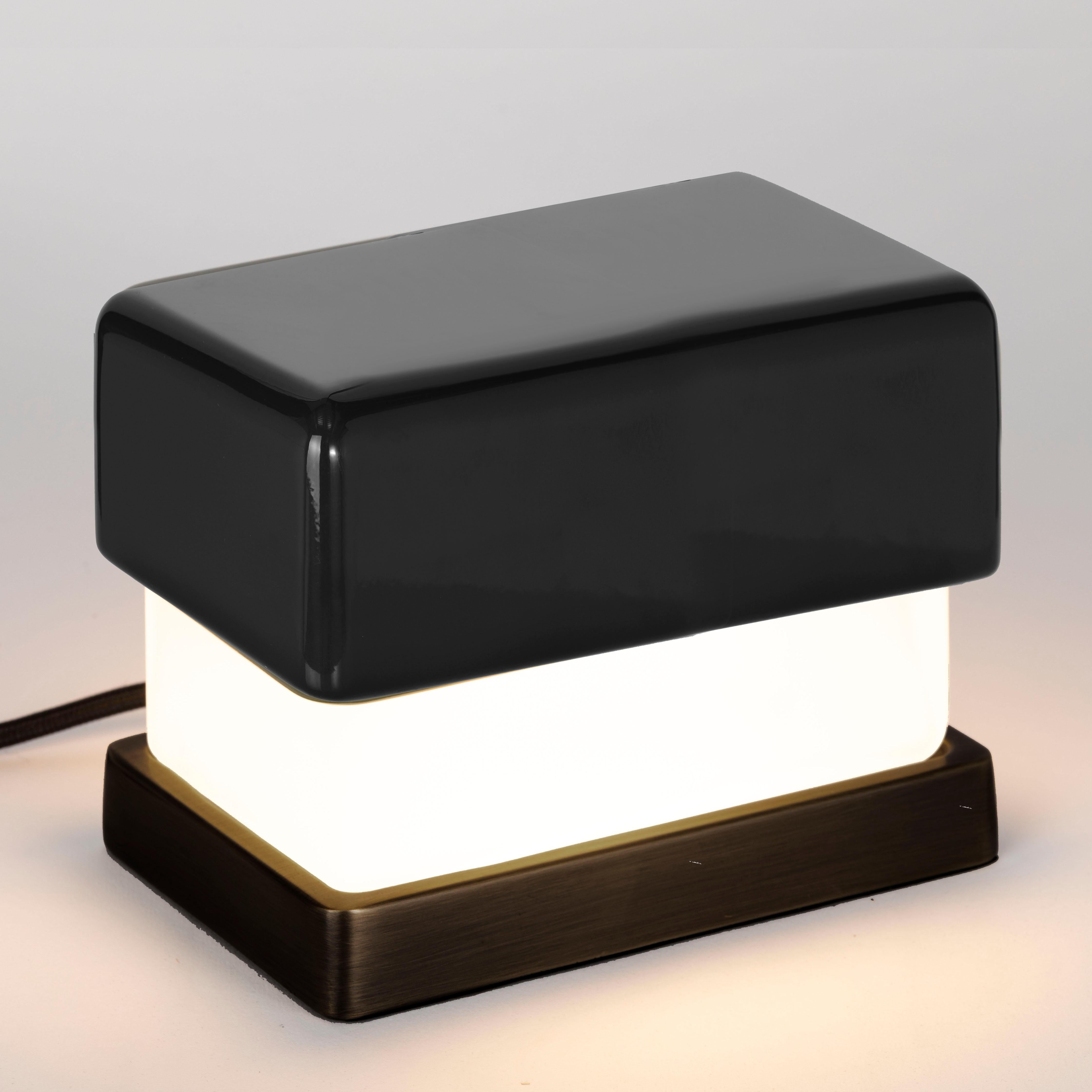 Kleine Tischlampe. Glänzend schwarz lackierte Holzkappe; satinierter Glasdiffusor. Sockel aus massivem Messing, brüniert. Schwarzes satiniertes Kabel.
Entworfen von Matteo Bianchi für Officina Luce.

1 x LED-Modul mit Transformator, alles inklusive. 