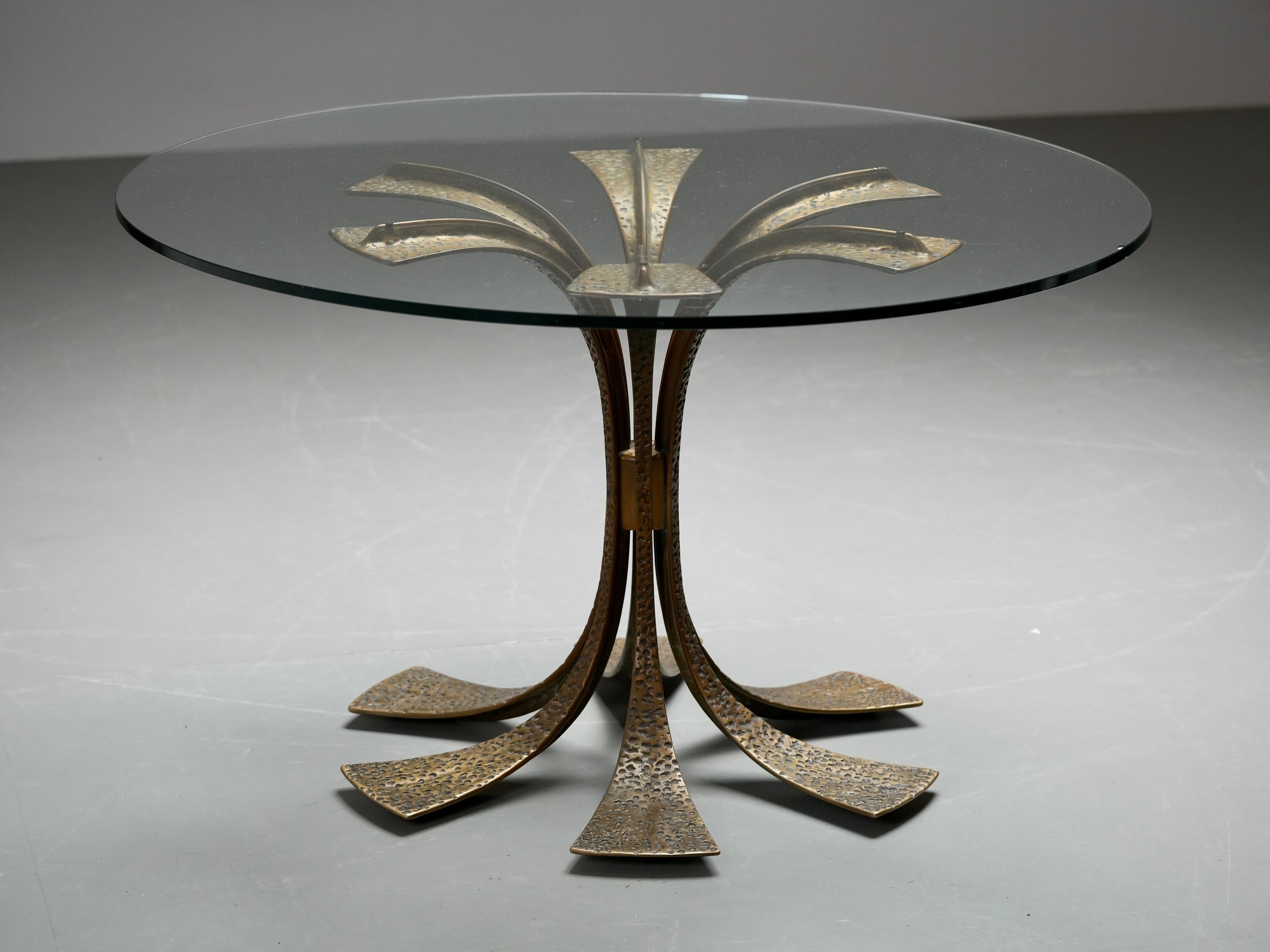 Rare round dining table by Luciano Frigerio, crafted in Italy in the late 1960s. The base is made of solid hammered brass with a beautifully sculptural, organic form. Six arched legs radiate outward in perfect symmetry, meeting the floor in